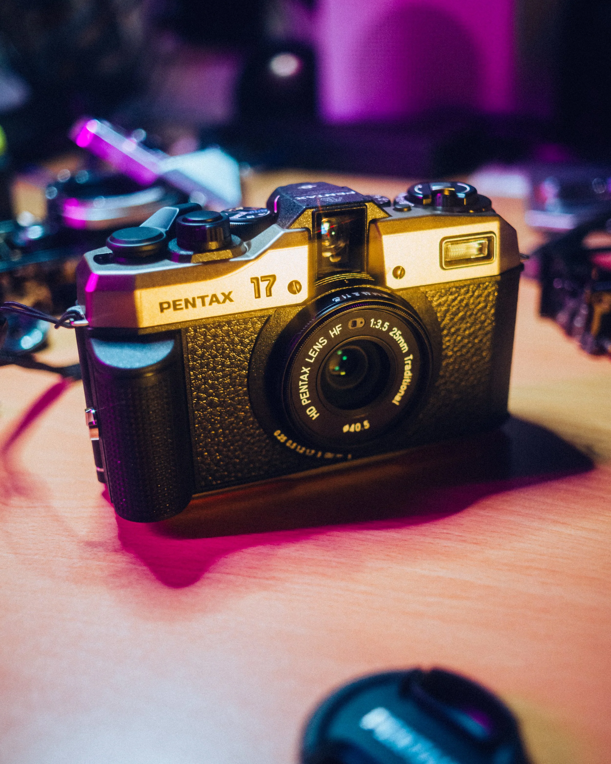 a close up of the Pentax 17 illuminated by pink and gold lighting