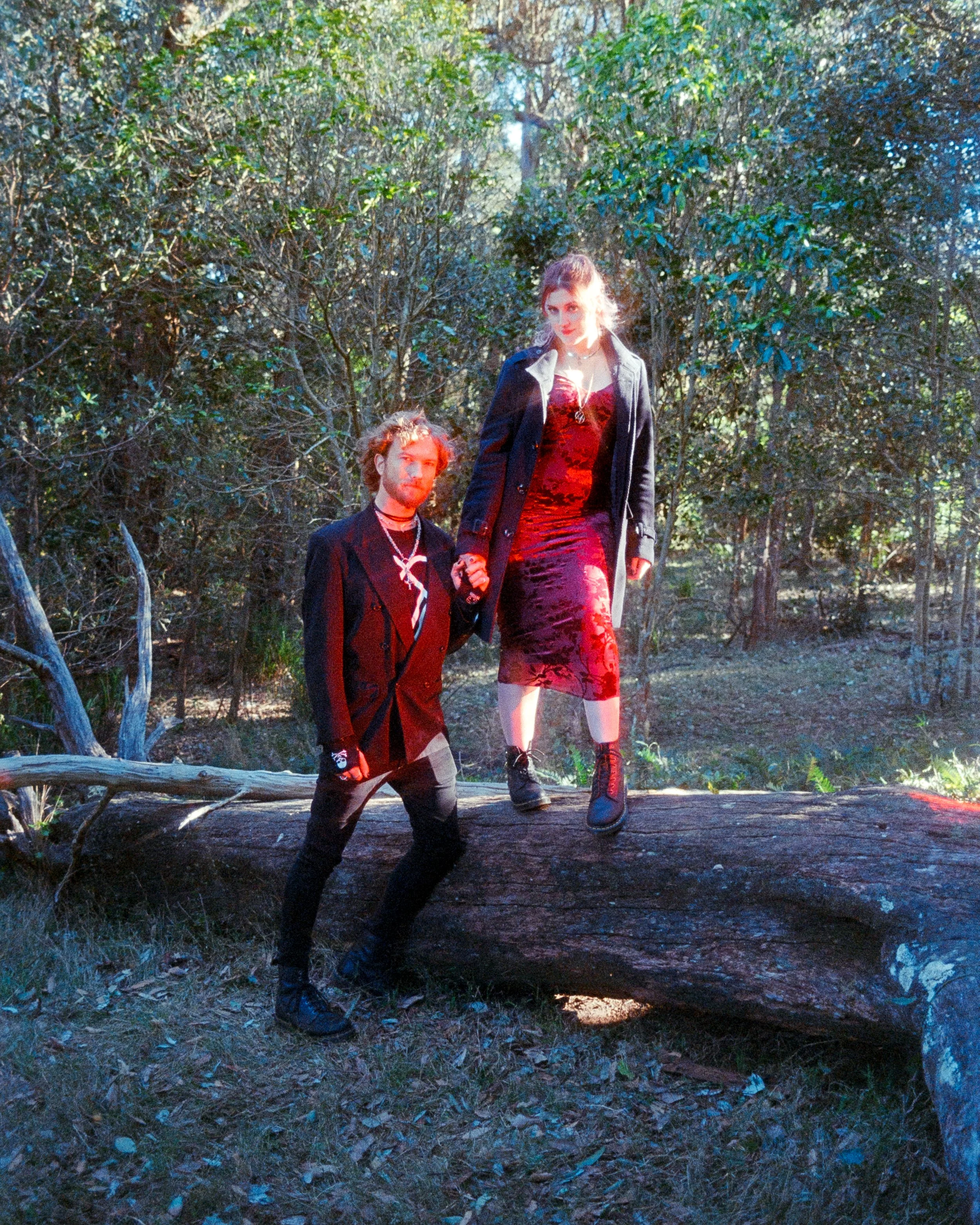 Couples portrait of a man and a woman, dressed in red and black, in the forest, lit by red RGB lighting, on 35mm Film - Ultramax