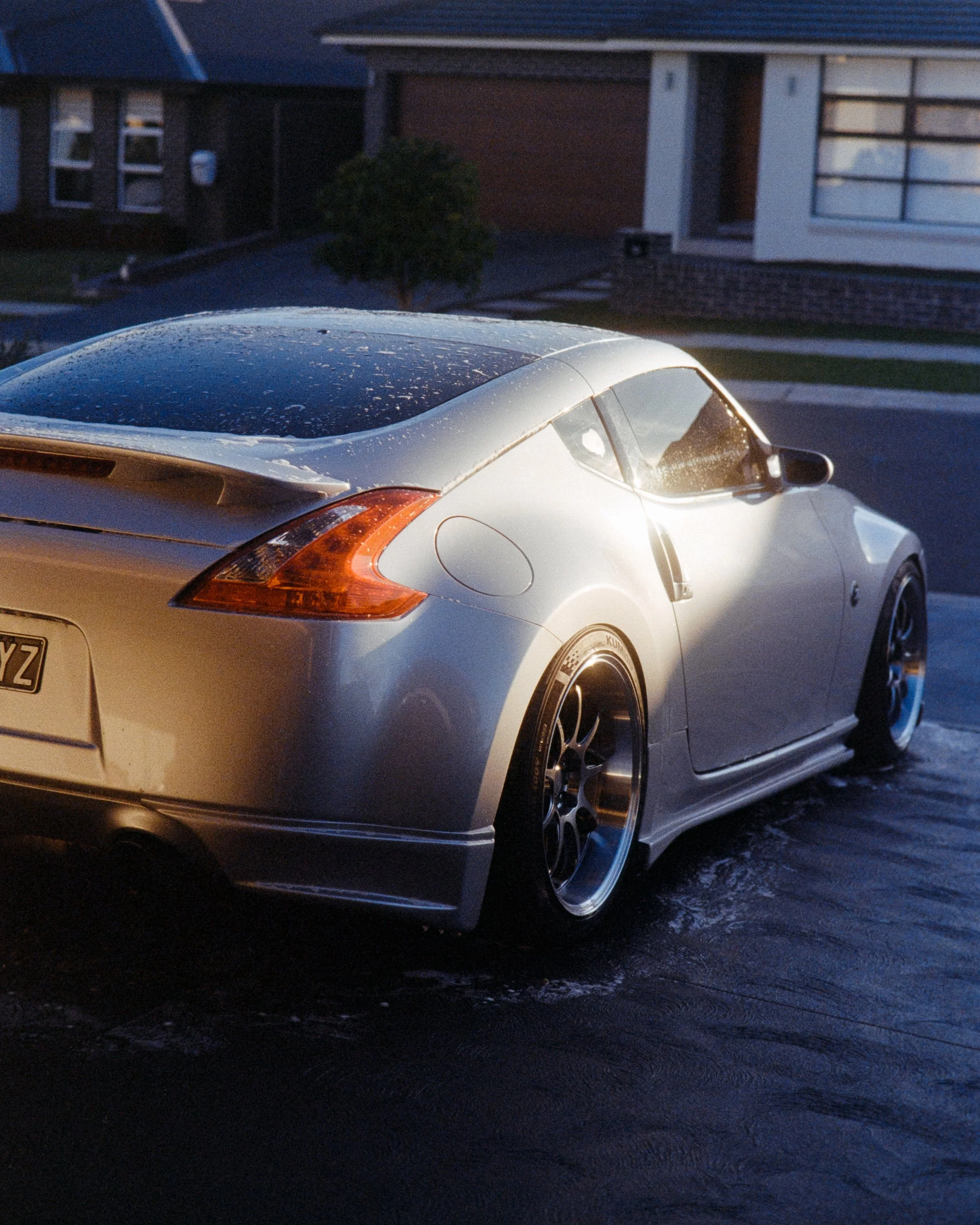 rear 3/4 shot of a Nissan 270z in glowing midday sun while being washed, shot on 35mm Film - Kodak Gold