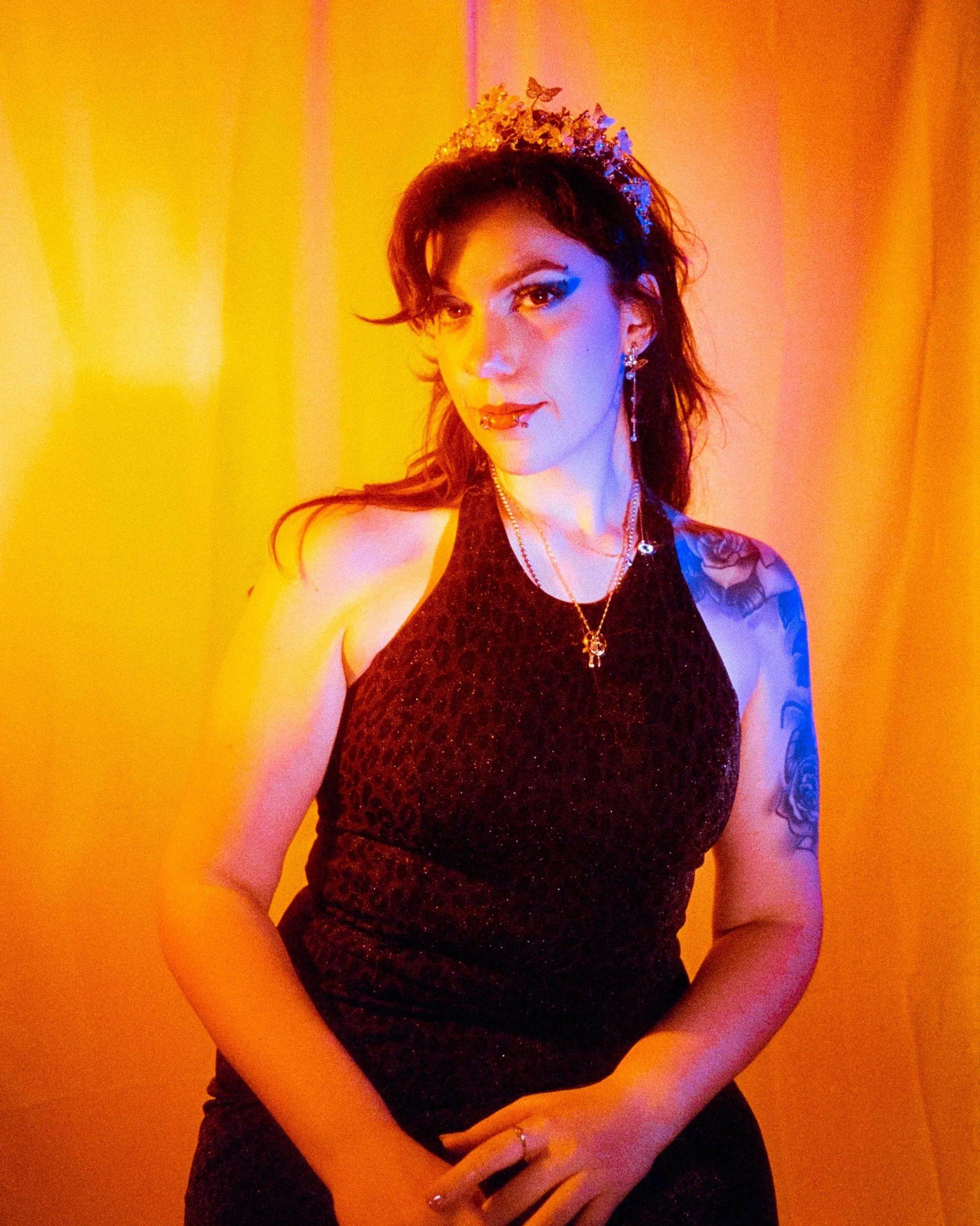 Josie dressed in a sparkling leopard dress, wearing a crown, with orange and blue lights on her, shot on 35mm Film - Ultramax