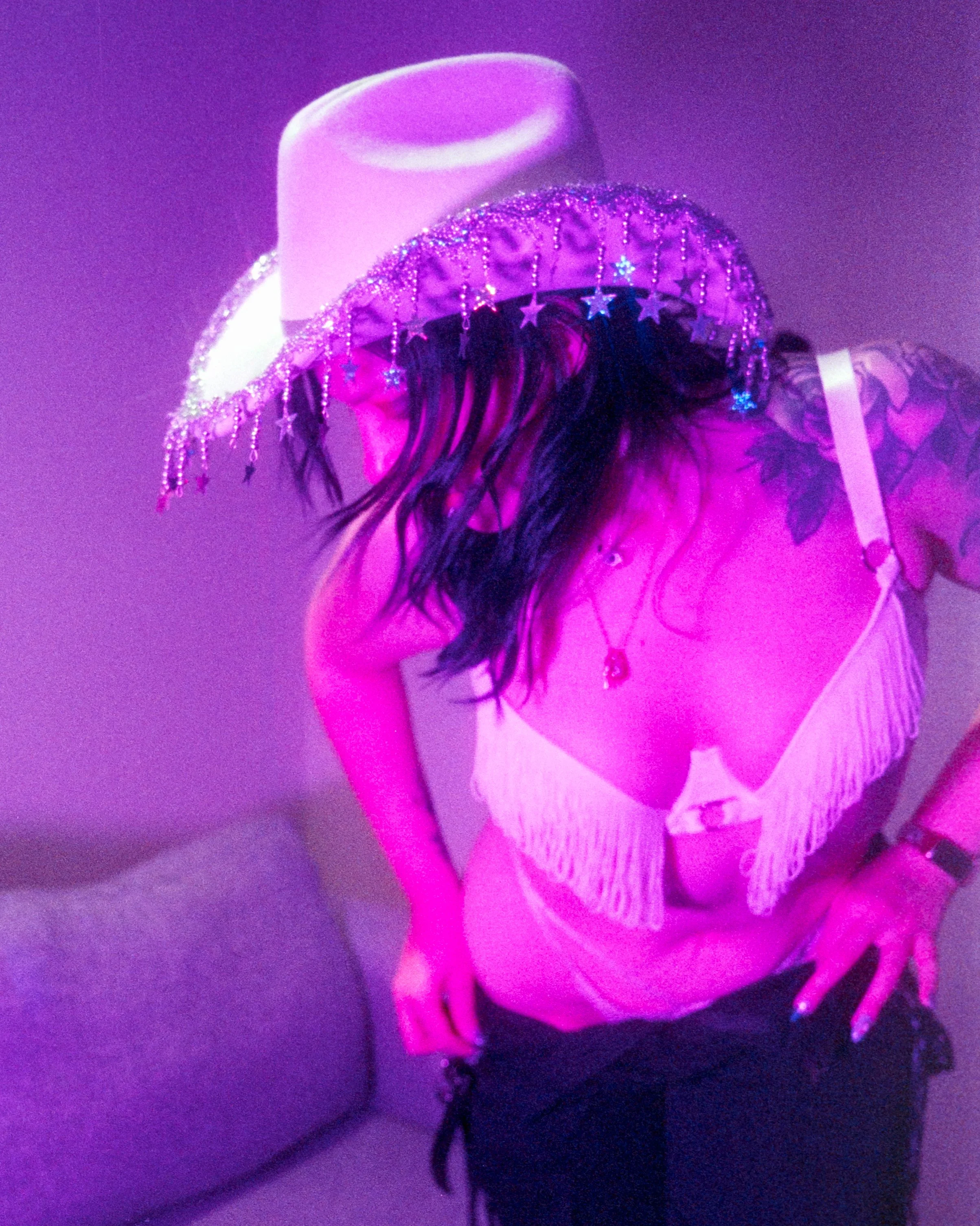 Close up action shot of Josie as she leans towards the camera, purple lighting on her, shot on 35mm Film - 400D Cinefilm