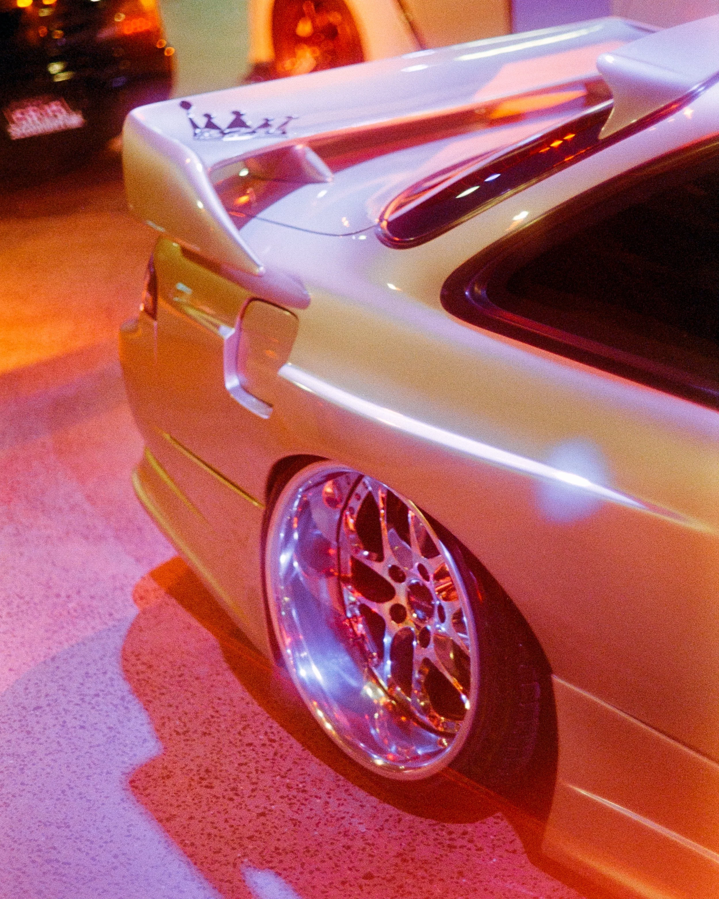 A glowing corner shot of a car and rims lit up by red RGB lights, on 35mm Film - Ultramax