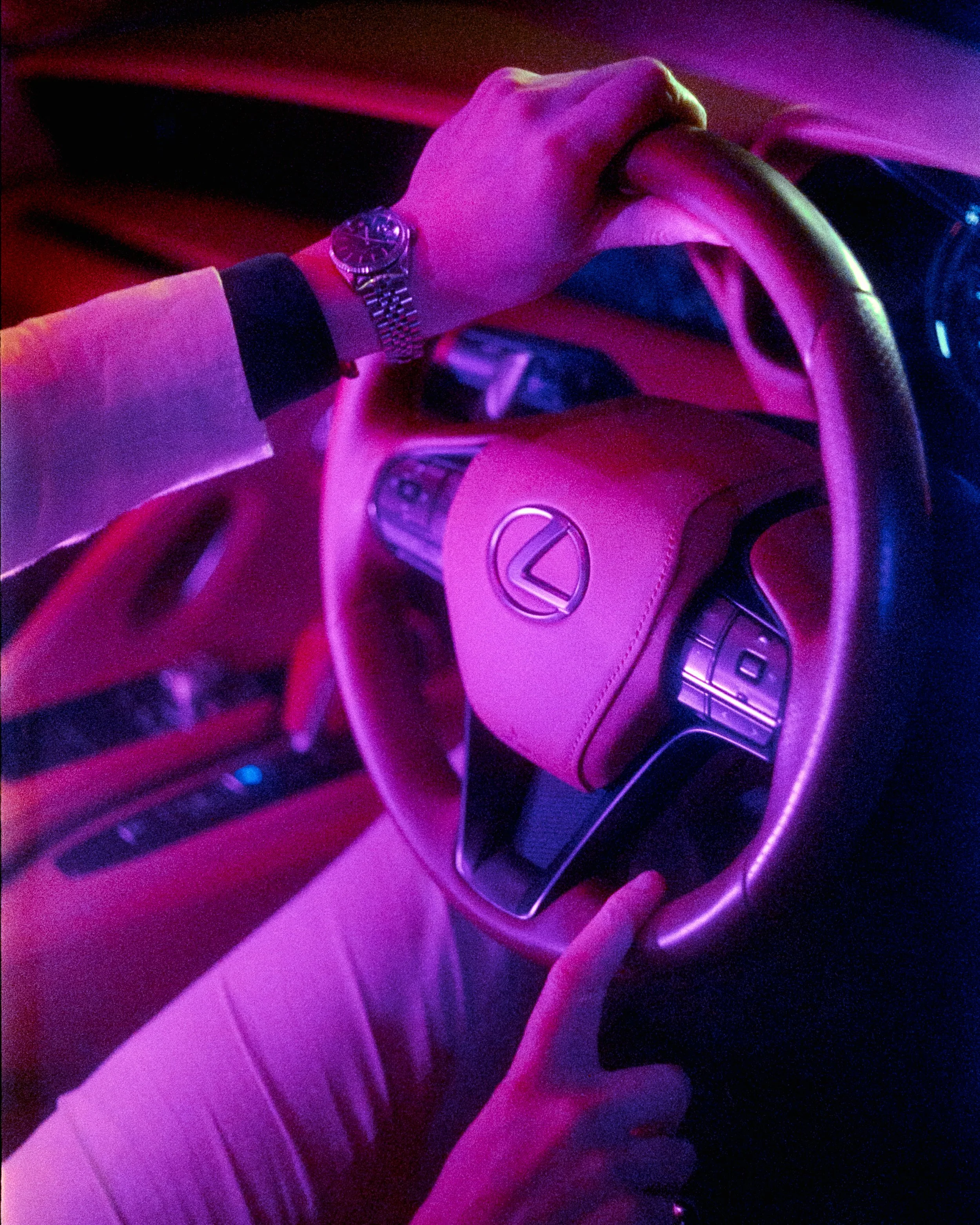 Close up of hands on a steering wheel, Lexus logo in the middle, vibrant magenta colouring across the whole frame, shot on 35mm Film - 500T Cinefilm