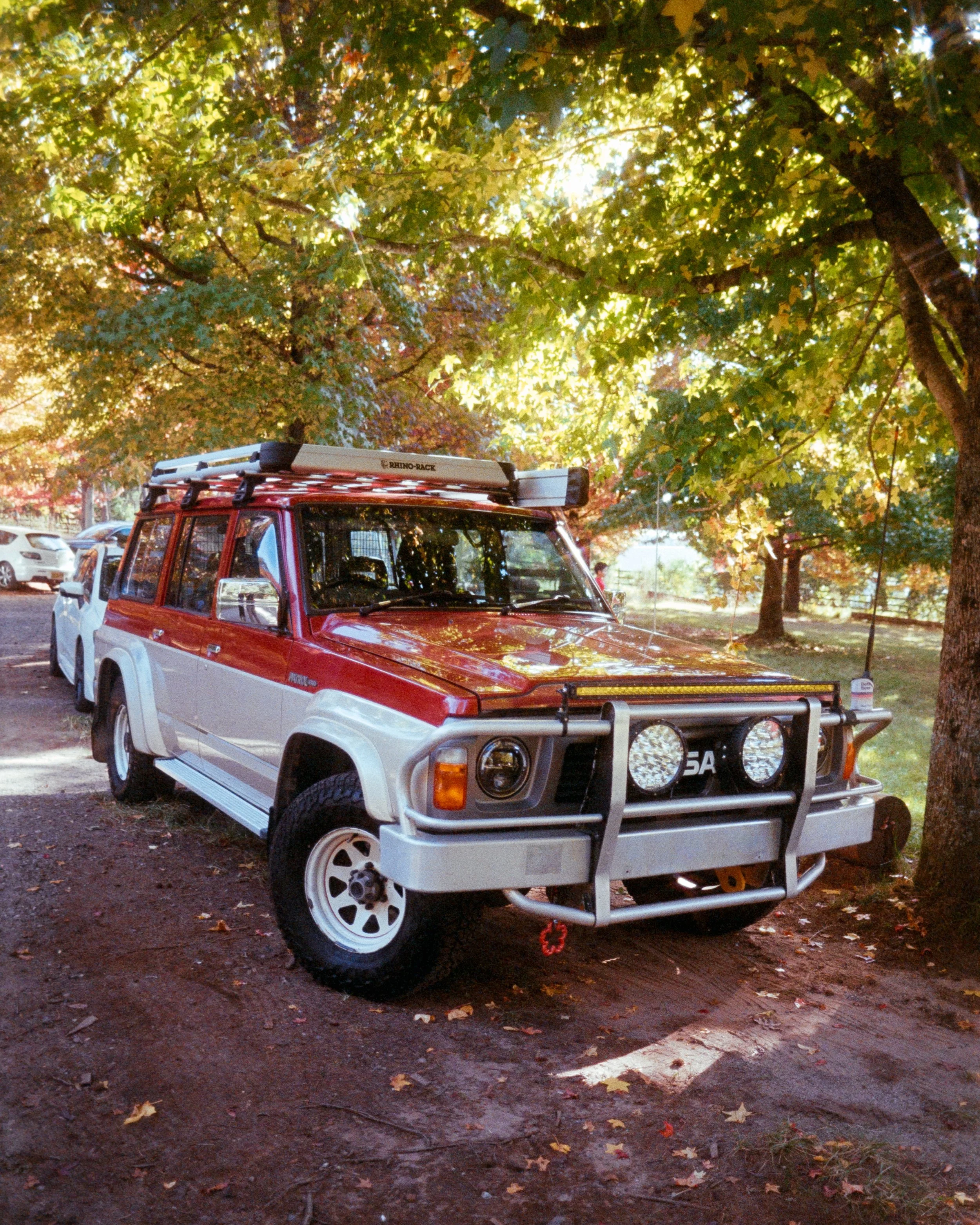 A close up of Scorpion, Josie's GQ Patrol, under glowing sunlight and trees full of Autumn leaves, shot on 35mm Film - Fuji 400