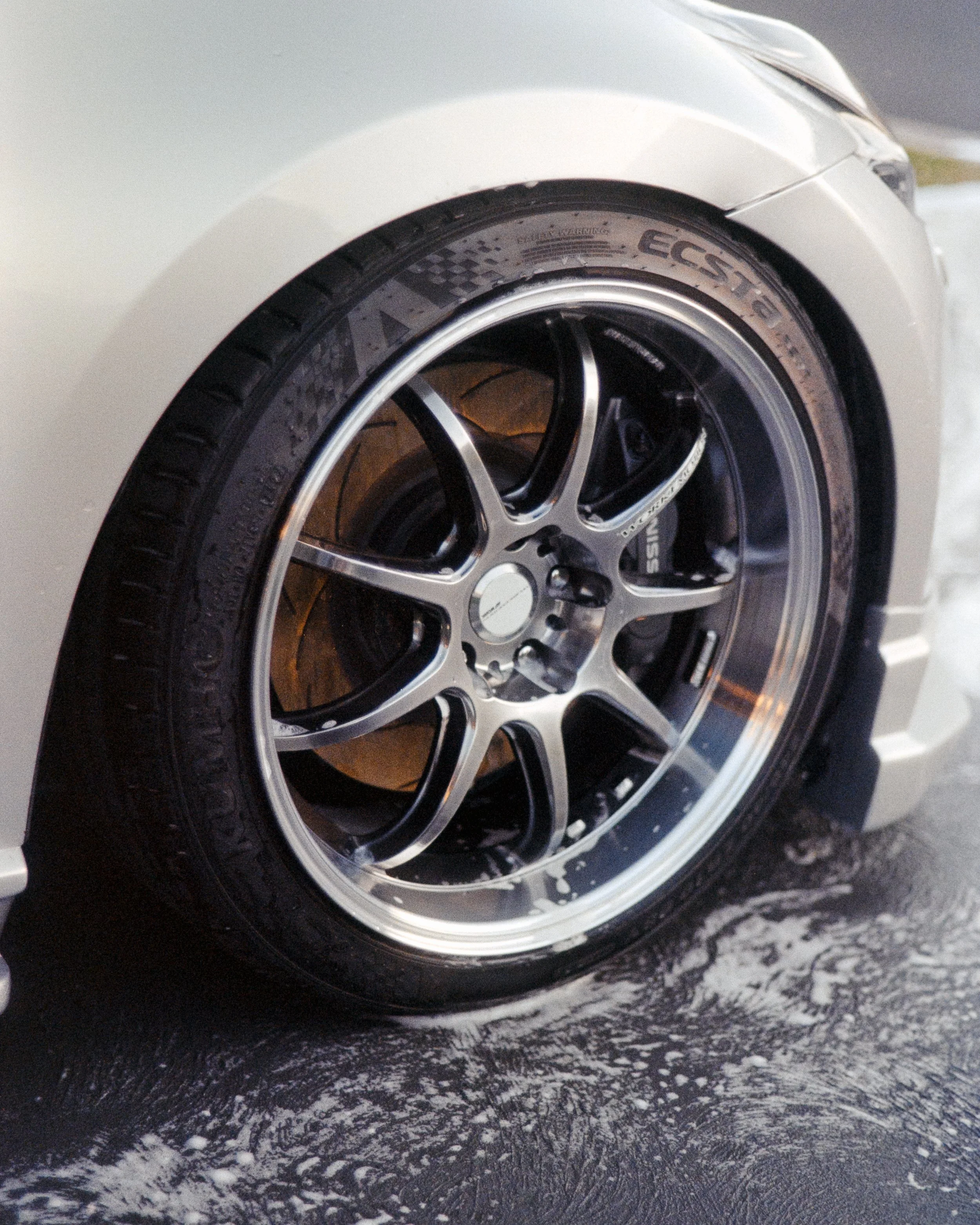 An up close shot of the rim of the Nissan 270z, still soapy from being washed, shot on 35mm Film - Kodak Gold