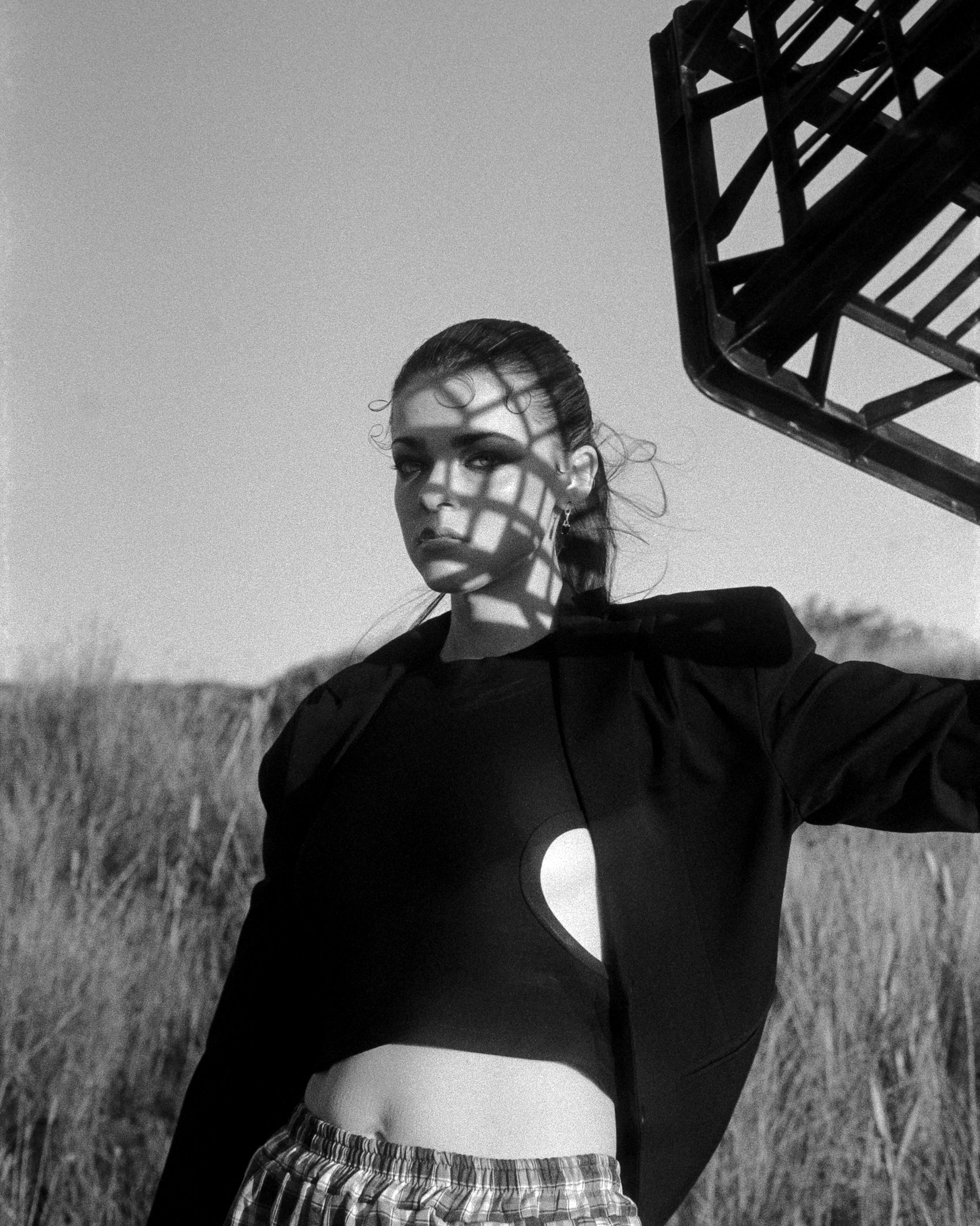 Elle Farrow, dressed in a suit, holding up a milk crate to create dramatic shadows on her face, on 35mm Film - Fomapan 400