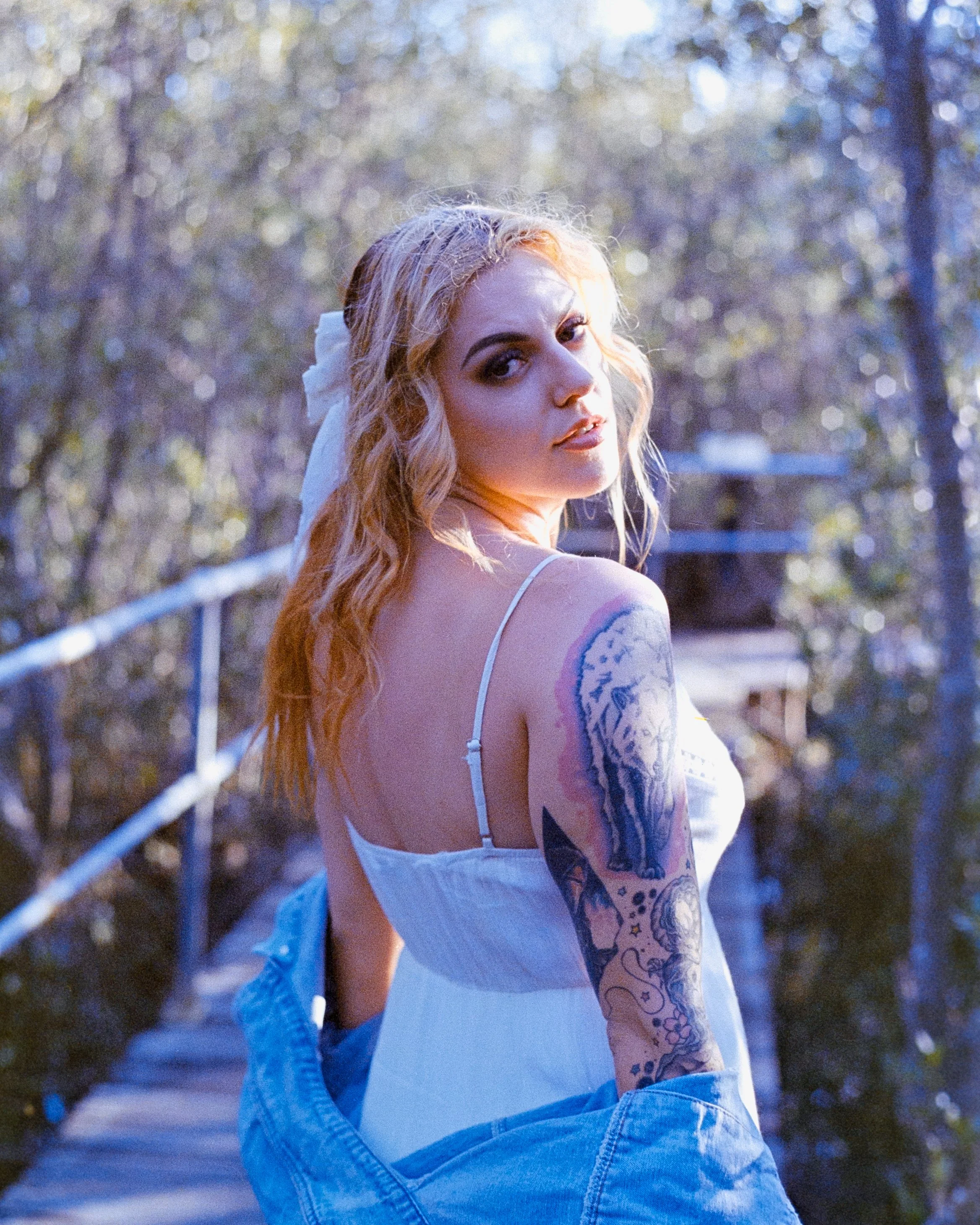 a soft feminine woman wearing white, looking over her shoulder while golden sunlight softens her features, on 35mm Film - Ultramax