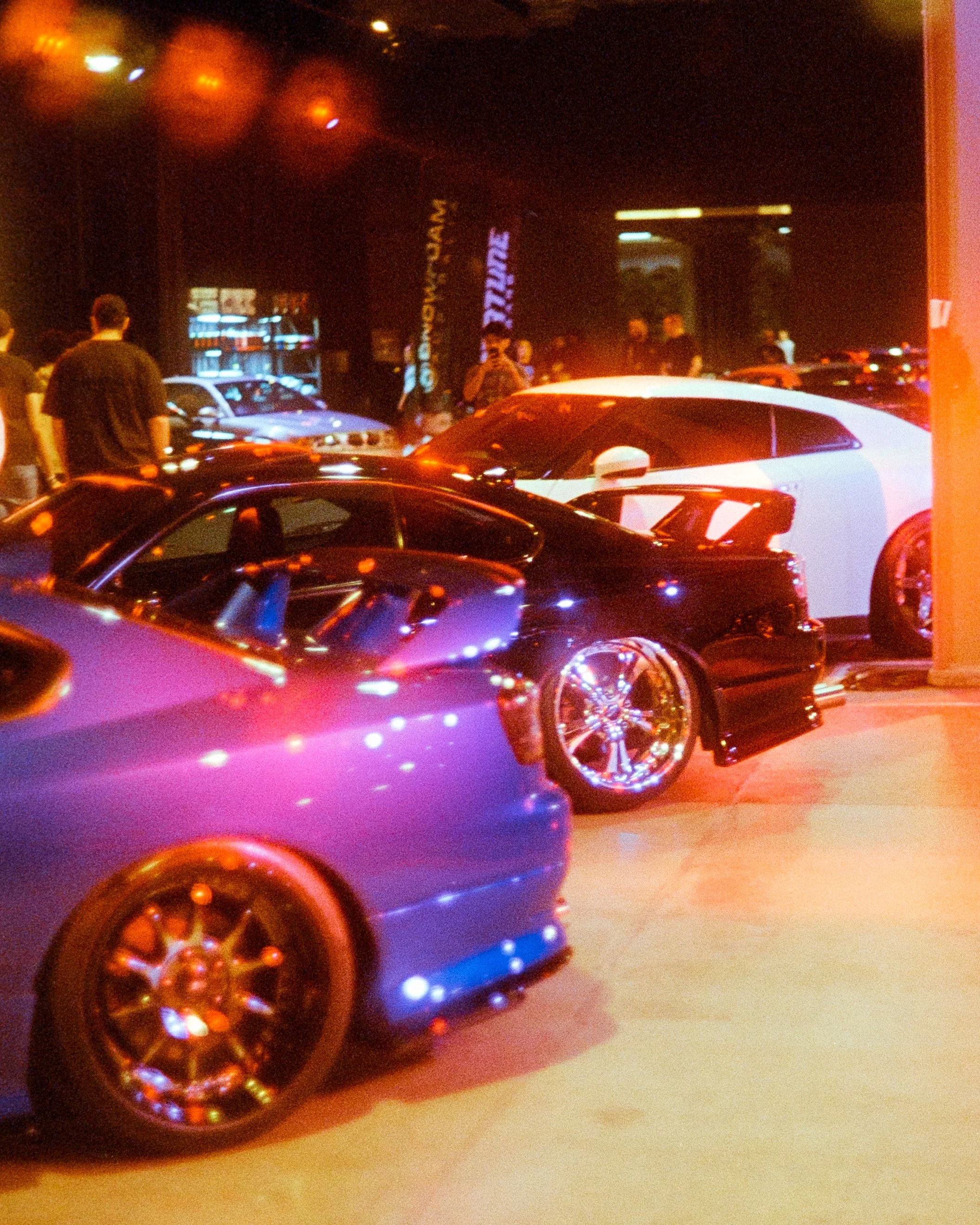 Rear corner shots of multiple cars, red lights bouncing off them, shot on 35mm Film - Ultramax