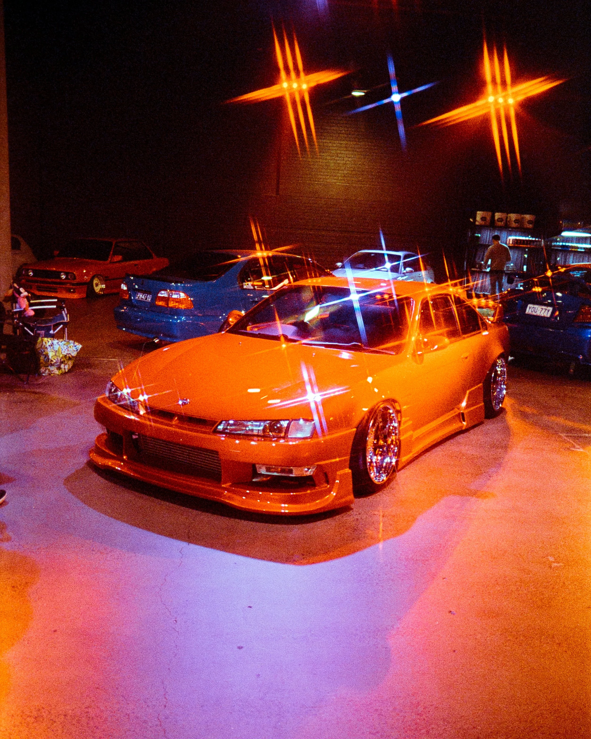 A red car at a car event, starbursts on the lighting, RGB lights in red and blue, on 35mm Film - Ultramax