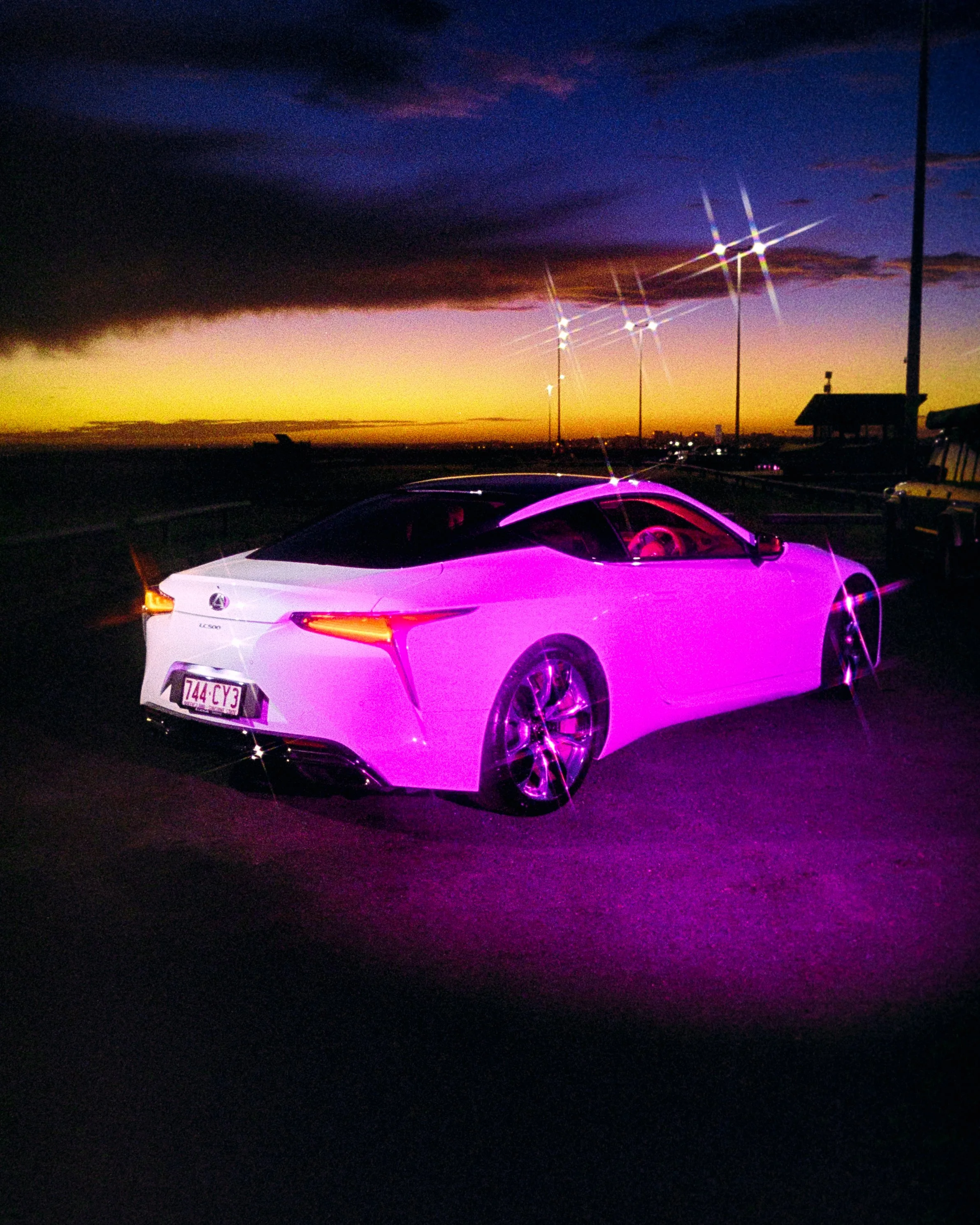 A glowing sunset photo combined with RGB lighting to create a beautiful intense 80's aesthetic. The lexus is pink, while the sky is vibrant yellow and blue. Shot on 35mm Film - Ultramax