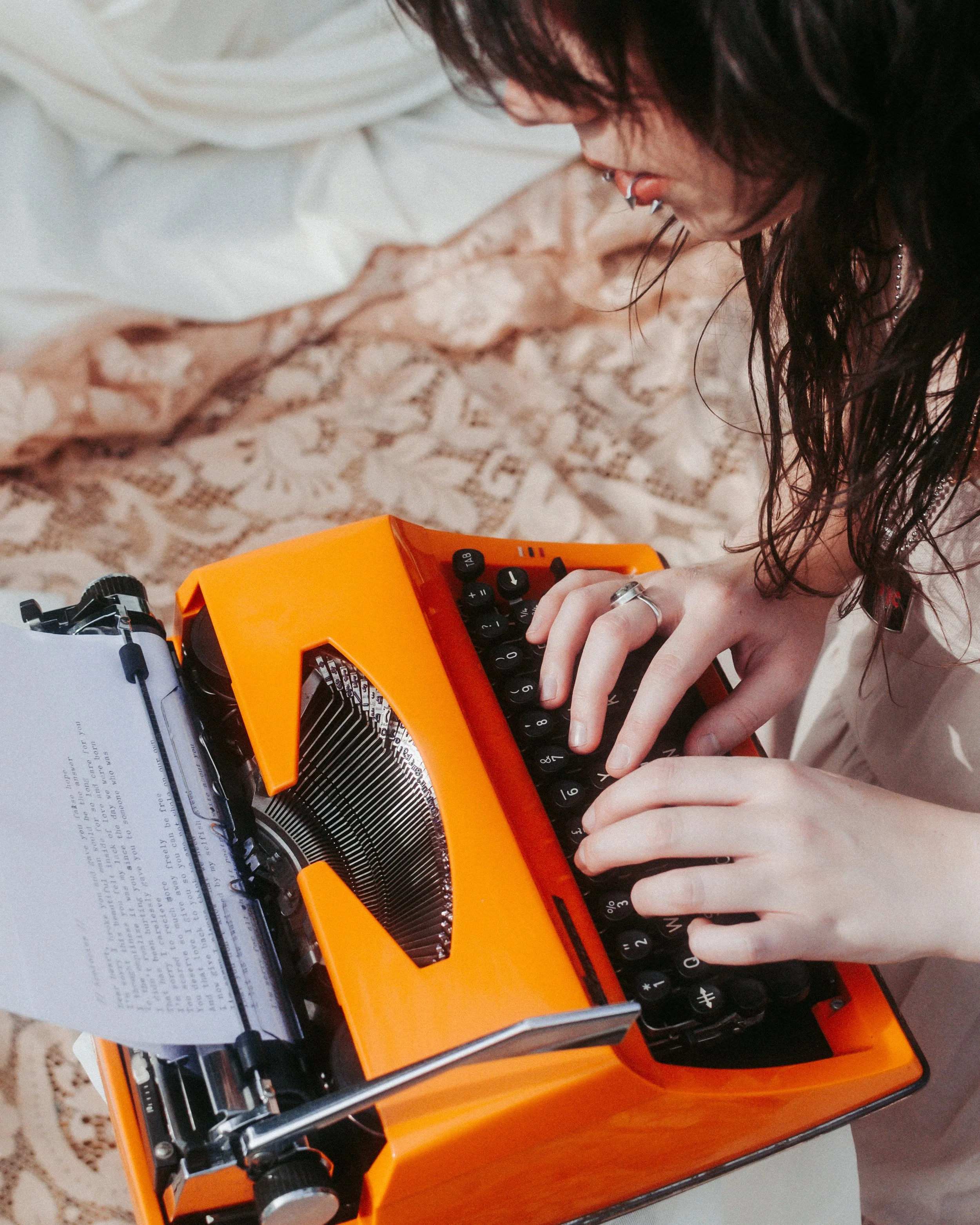 A close up of Josie typing up poetry on her orange typewriter