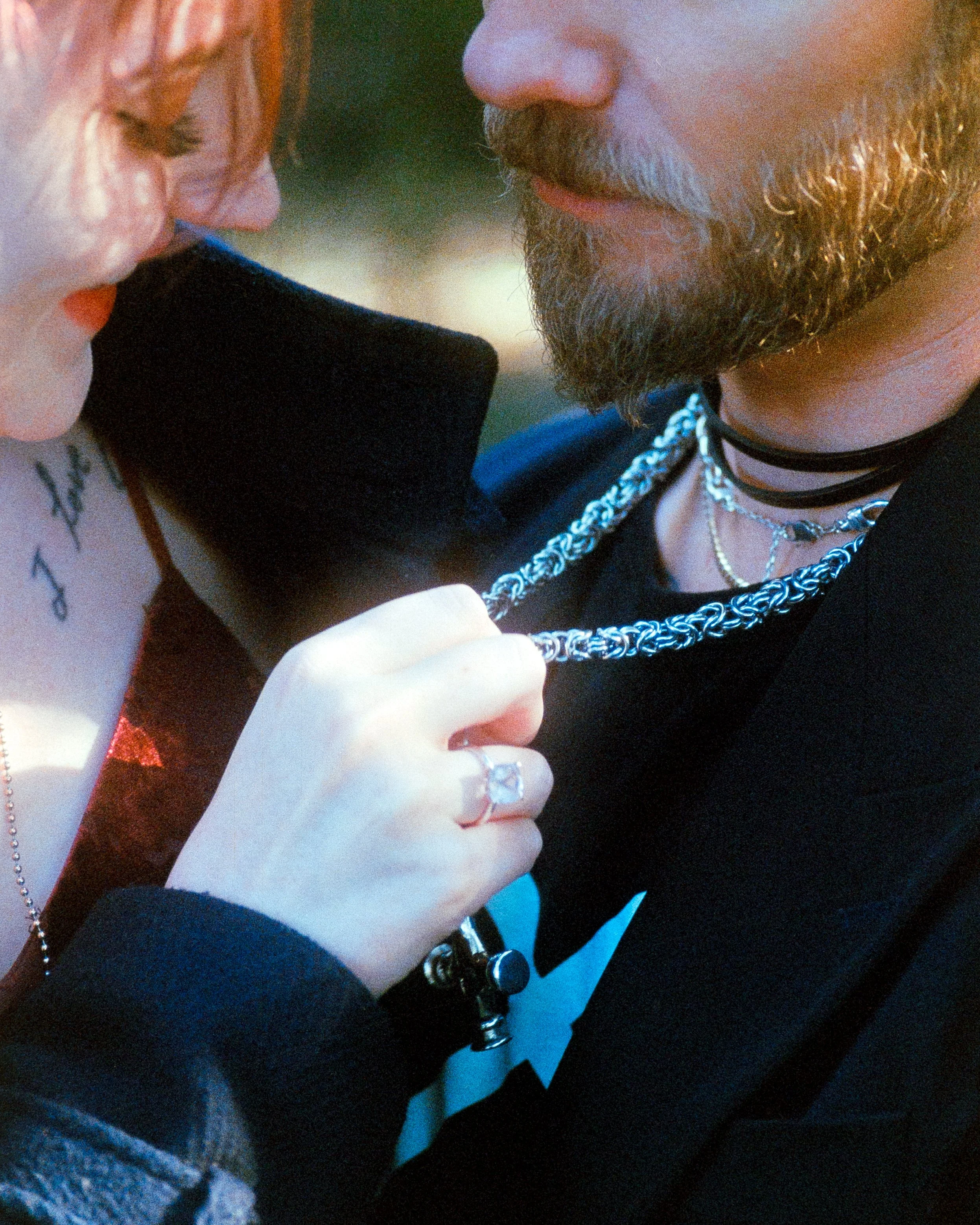 Close up of a female's hand with a ring on her finger, pulling gently at her partners necklace while they have an intimate moment, captured on 35mm Film - Ultramax