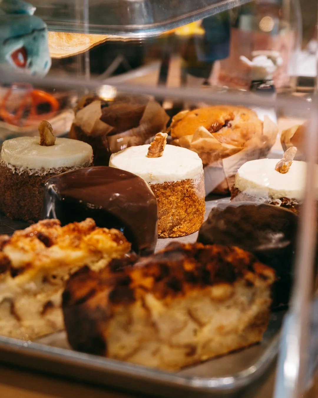 Assortment of pastries including cupcakes, cookies, croissants, and brownies displayed in a bakery case.