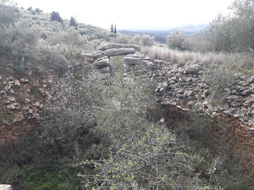 Ancient stone ruins with a large flat stone balanced on two vertical stones in a natural outdoor setting.