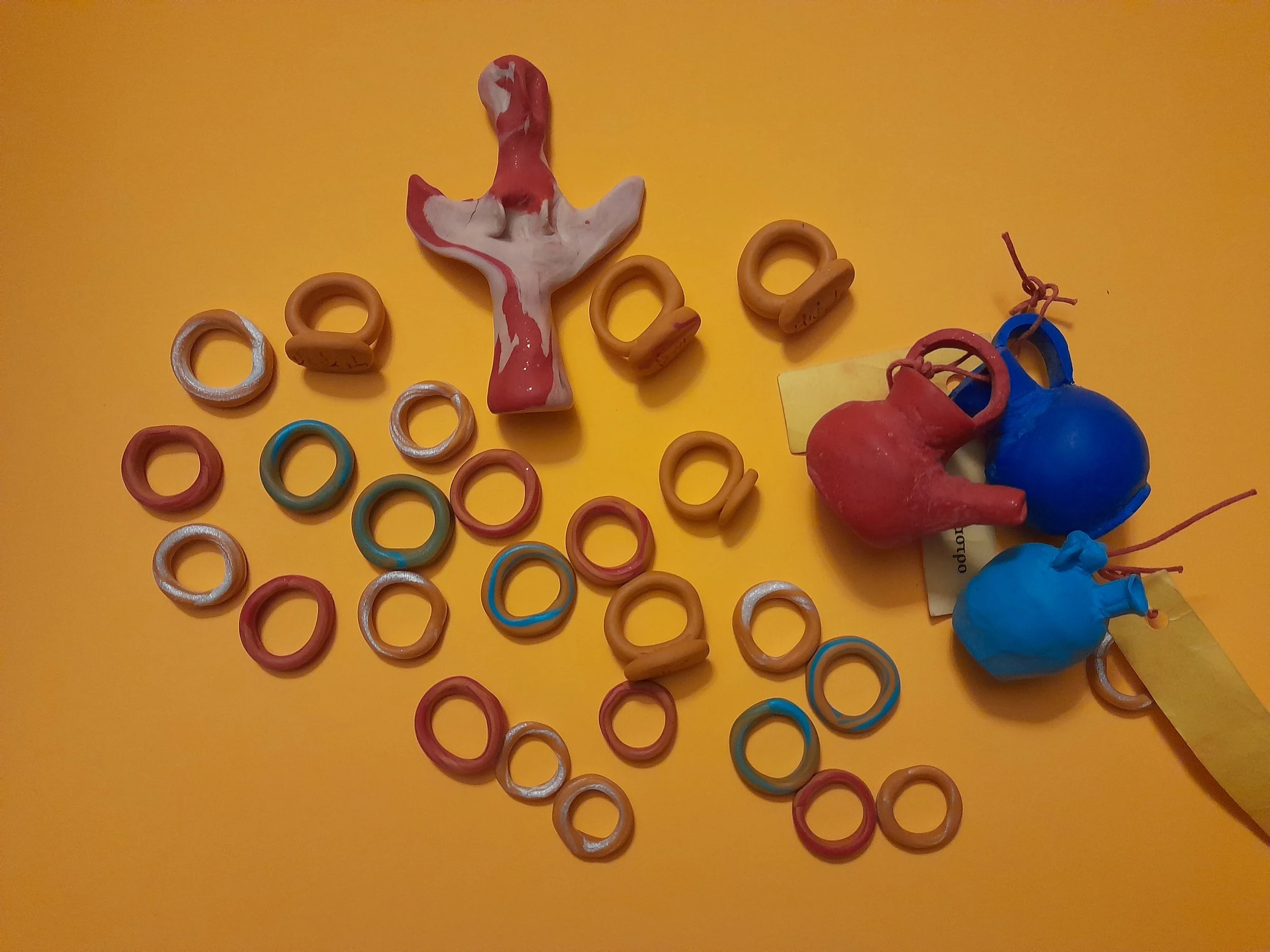 Colorful rubber rings and small toy balloons on a yellow surface, with a wooden and painted whale-shaped object.