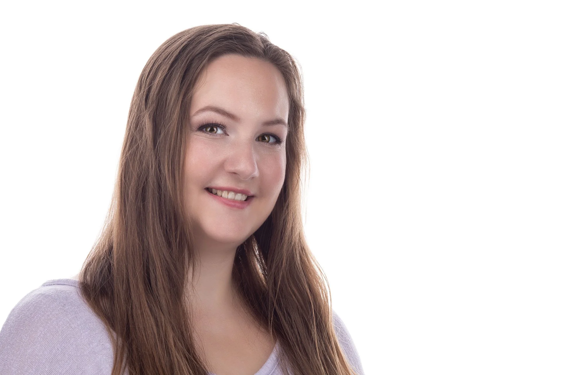 Et portræt af en smilende ung kvinde med langt brunt hår iført en lys lilla top, sat mod en hvid baggrund.