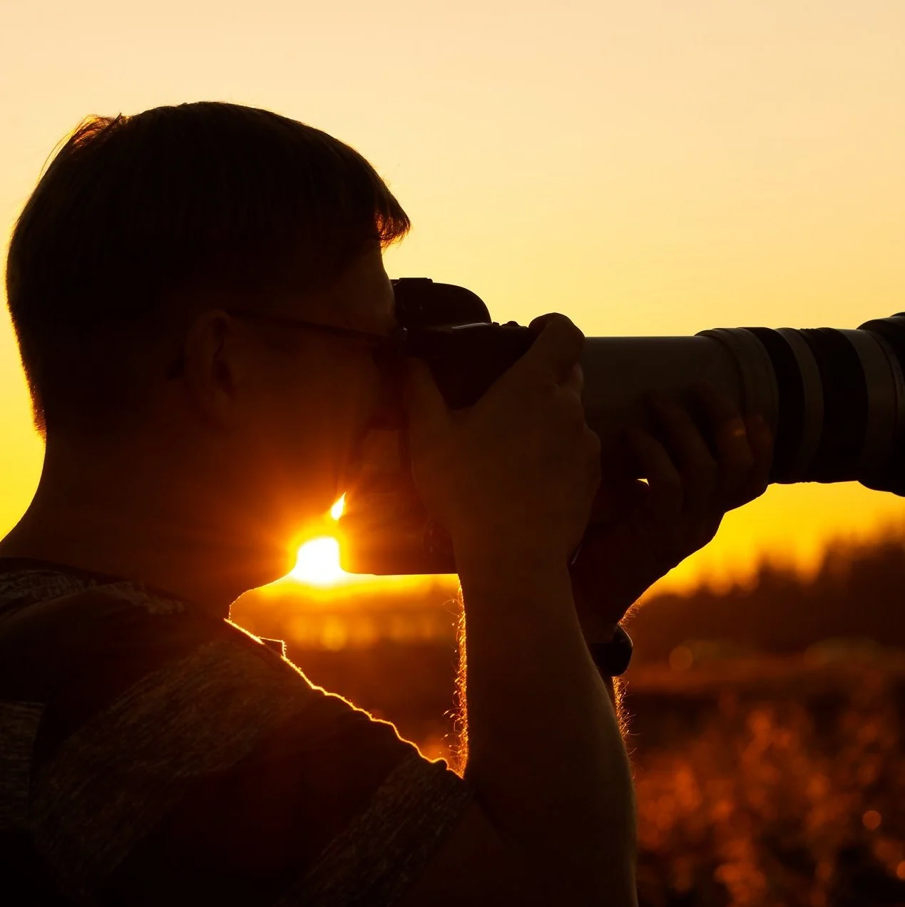 Person med kamera fotograferer mod solnedgang.