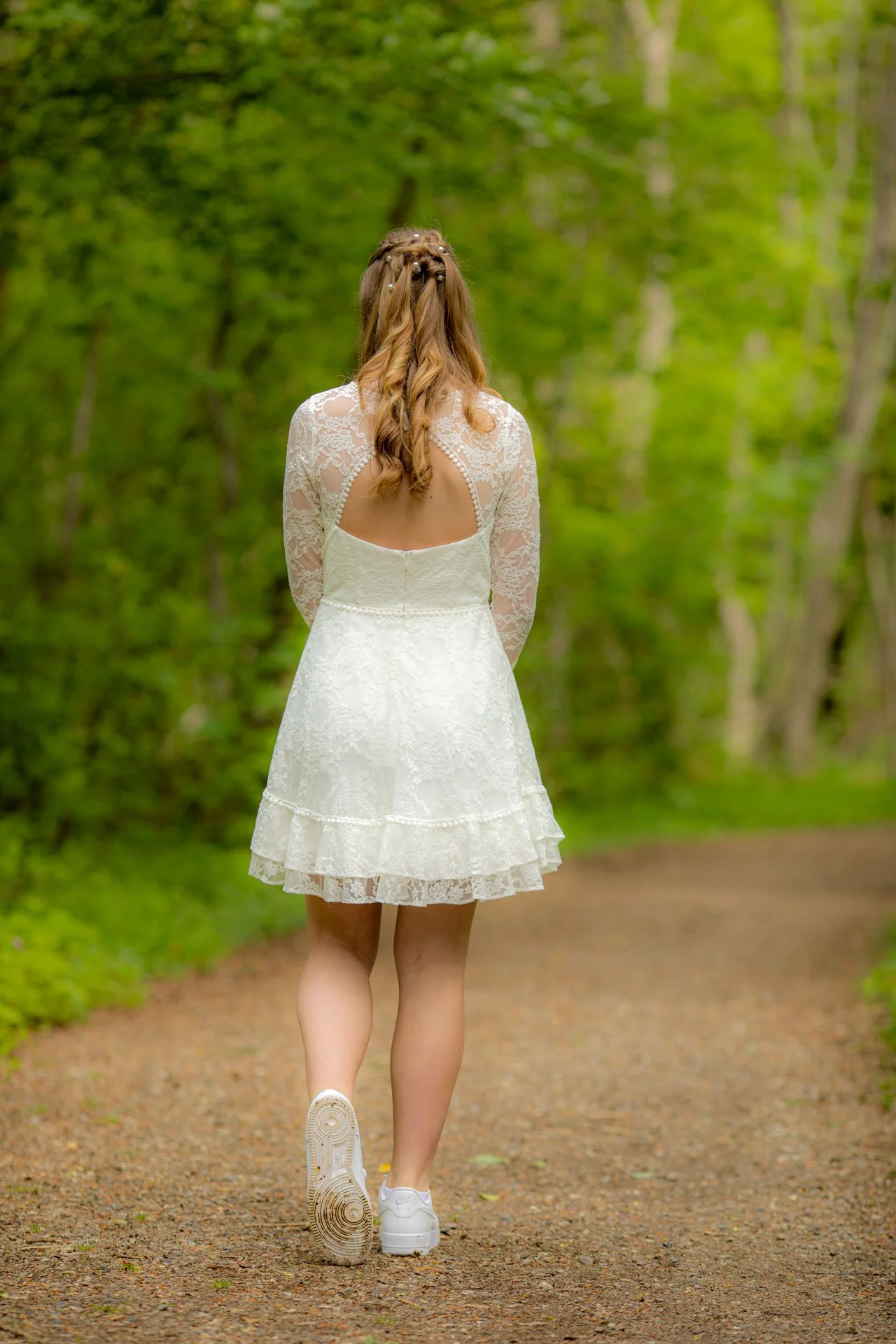 Kvinde i hvid kjole går væk i skov