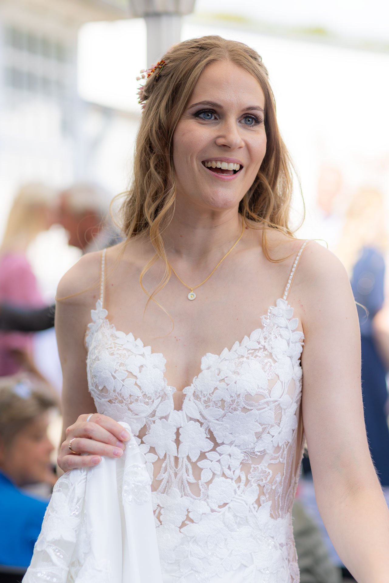 En kvinde i en hvid brudekjole smiler og ser lykkelig ud.