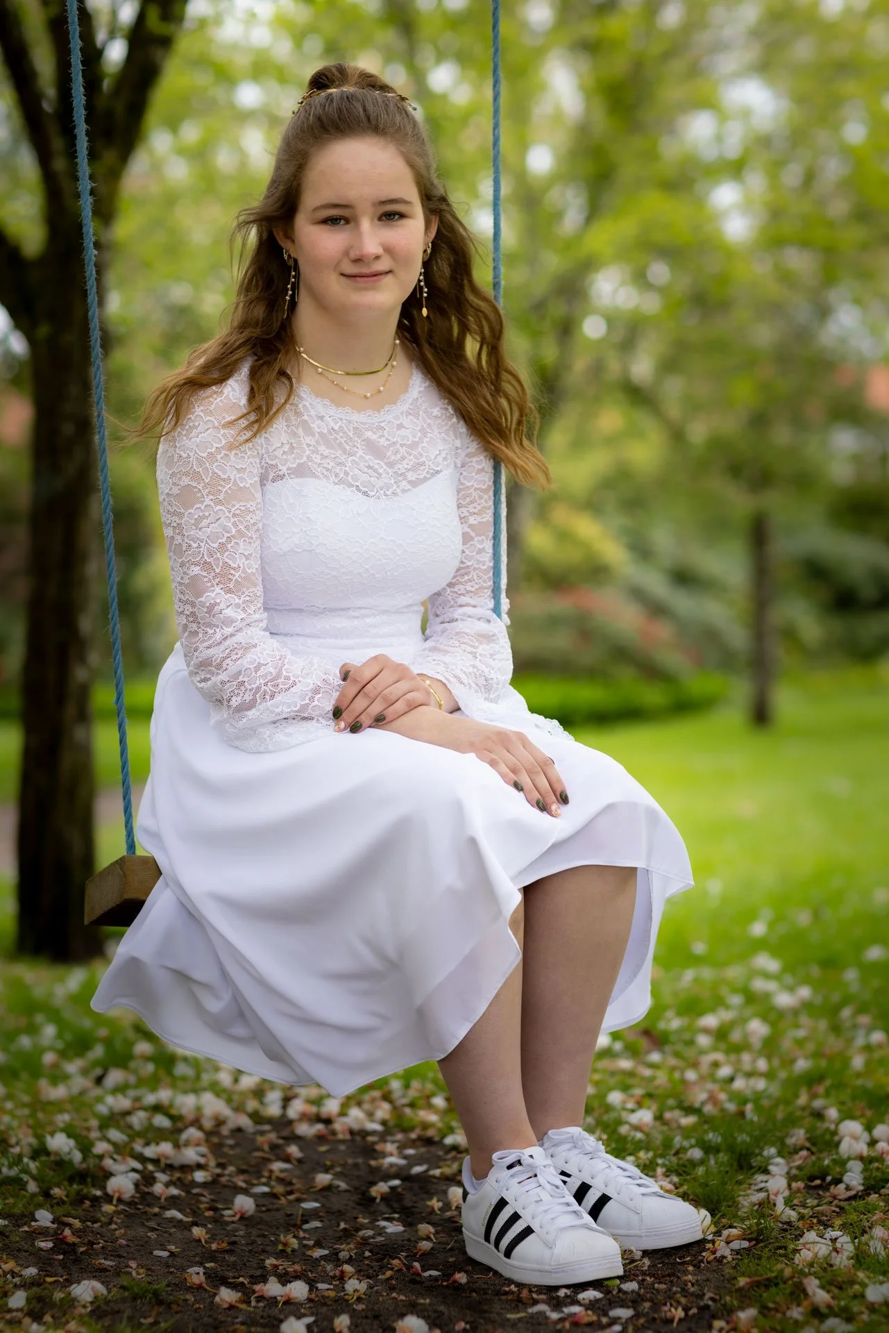 Ung kvinde sidder på en gynge i en grøn park med blomster på jorden.