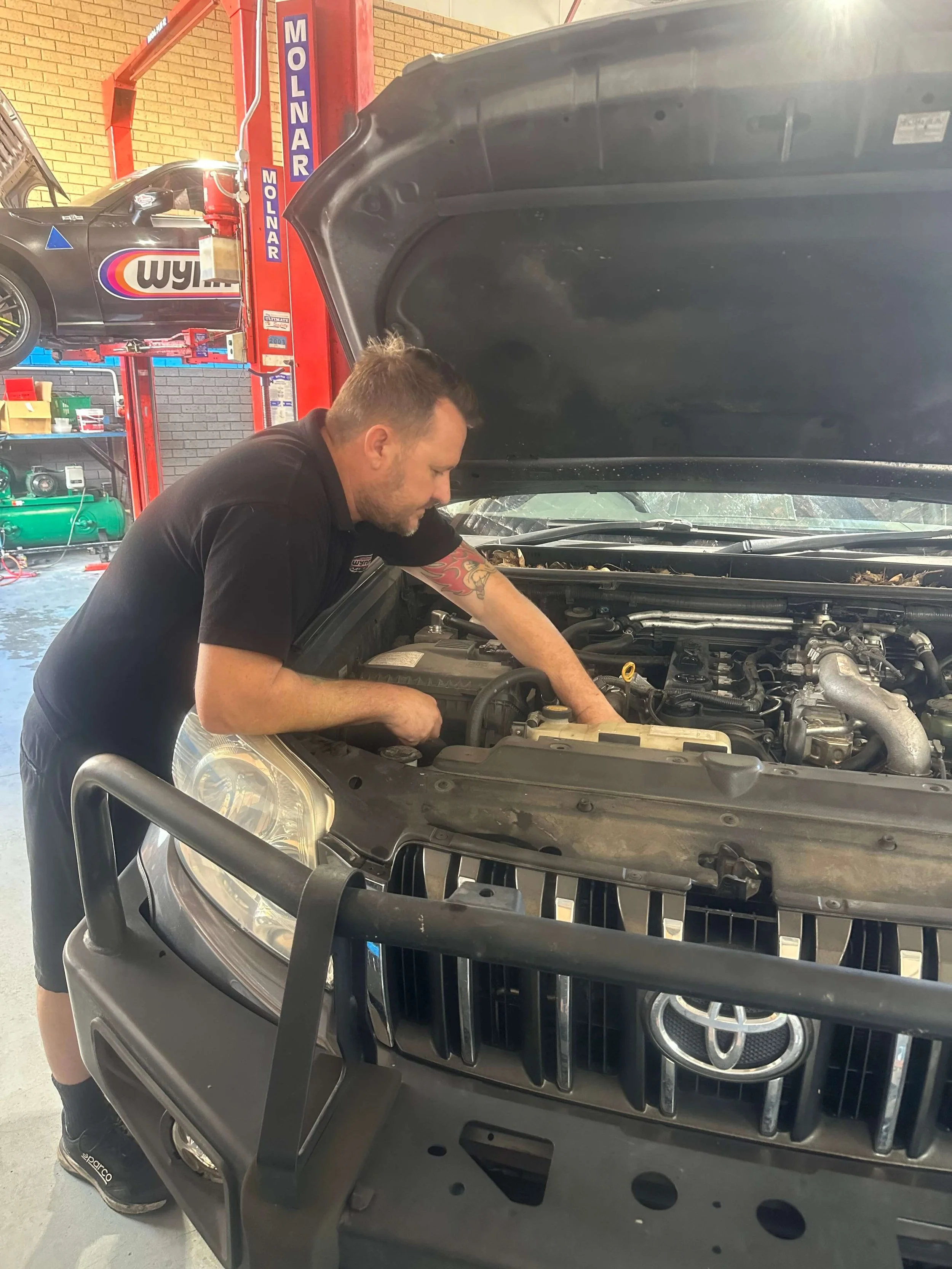 A man working on a car engine at an auto repair shop. Mechanic near me Stafford.