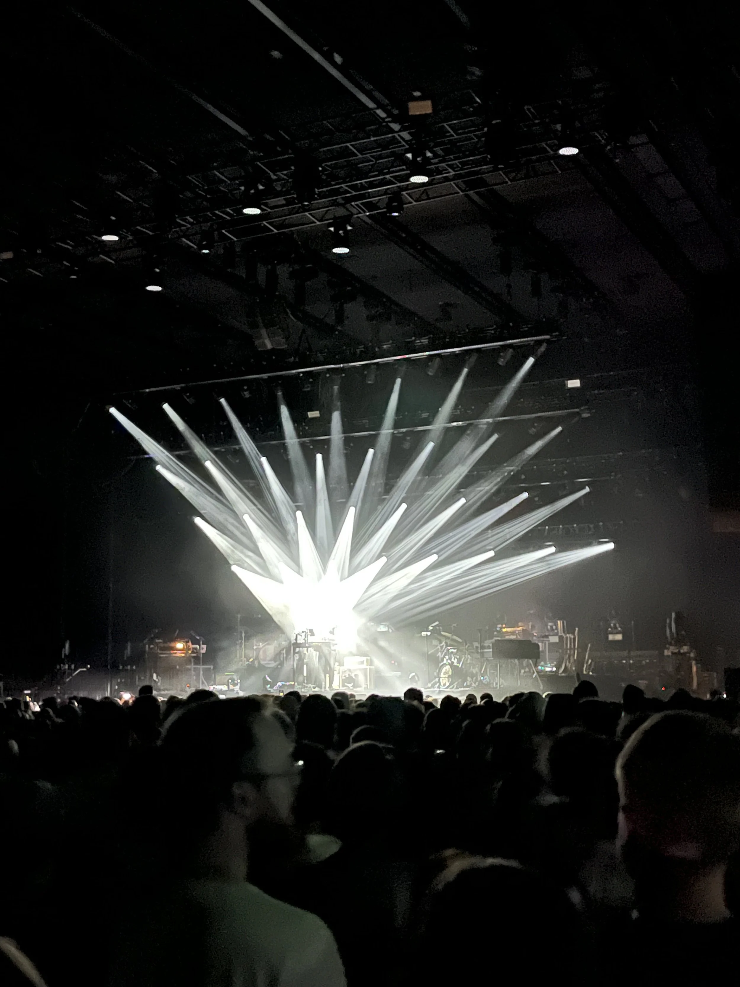 Stage with bright white lights and audience in foreground at concert or event.