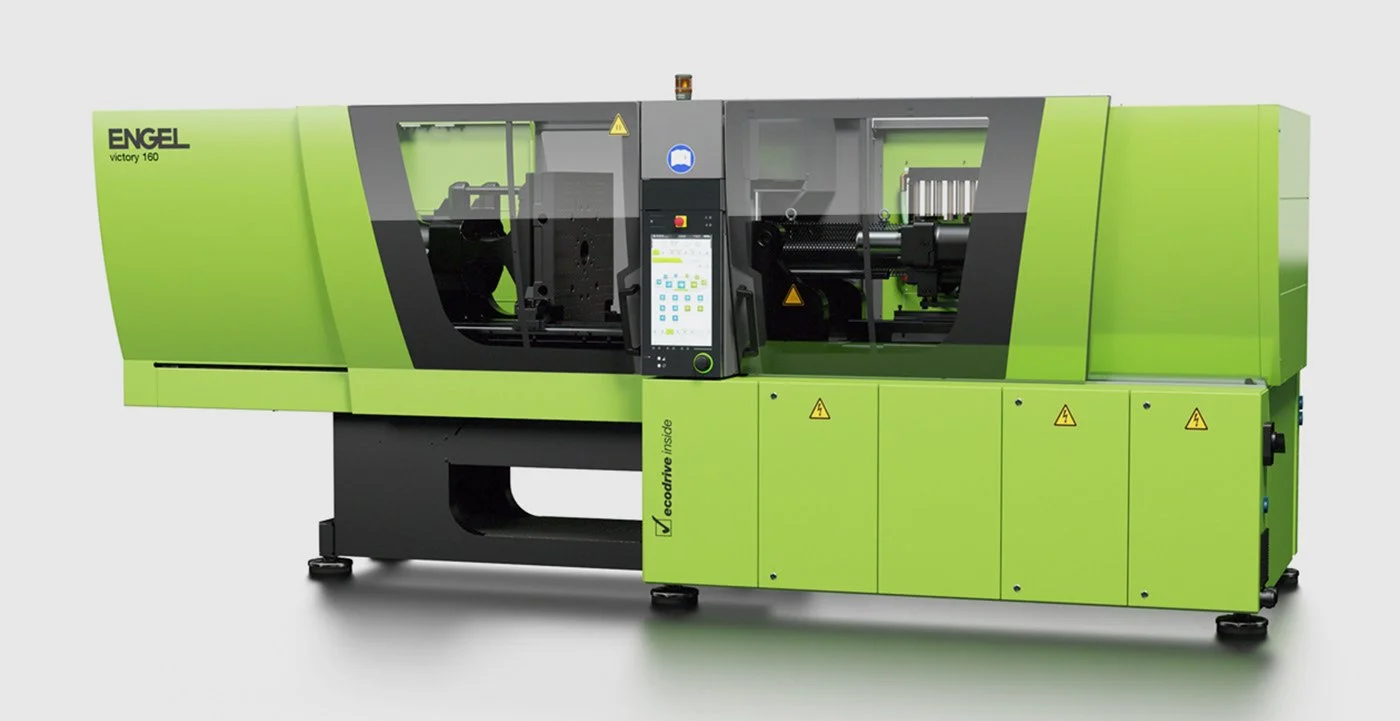 A large, green industrial injection moulding machine with a control panel in the centre and black safety panels on either side.