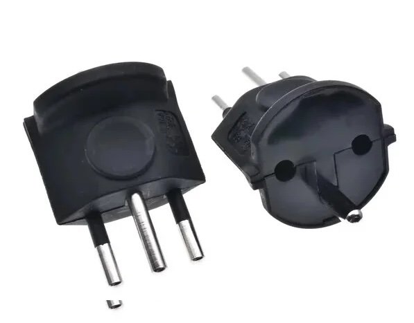 Zwei europäische Stecker mit entfernbaren Stiften, ein quadratischer Stecker und ein runder Stecker, aus schwarzem Kunststoff.