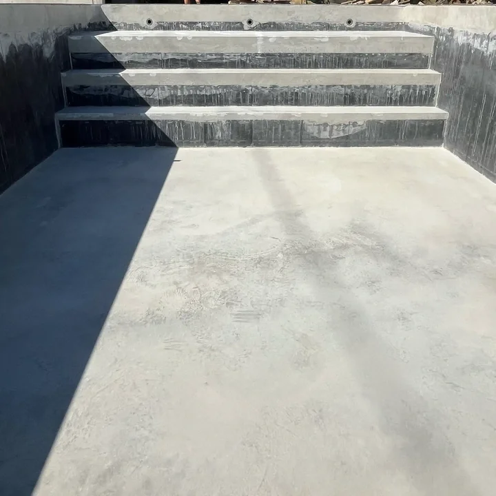 Escaliers en béton extérieur avec ombre, sans main courante, près d'une paroi.