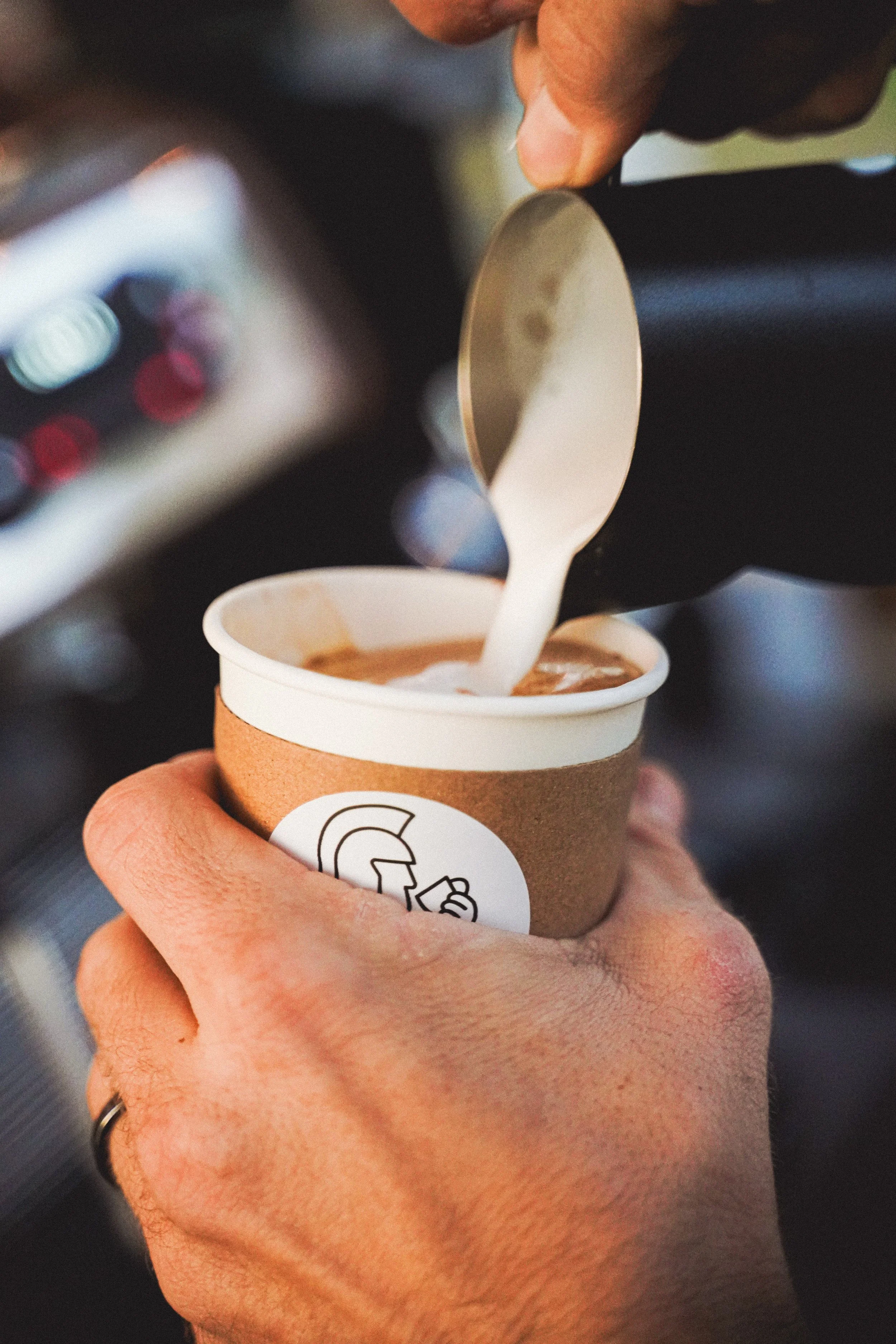 Pouring steamed milk from pitcher into Conlan Coffee cup