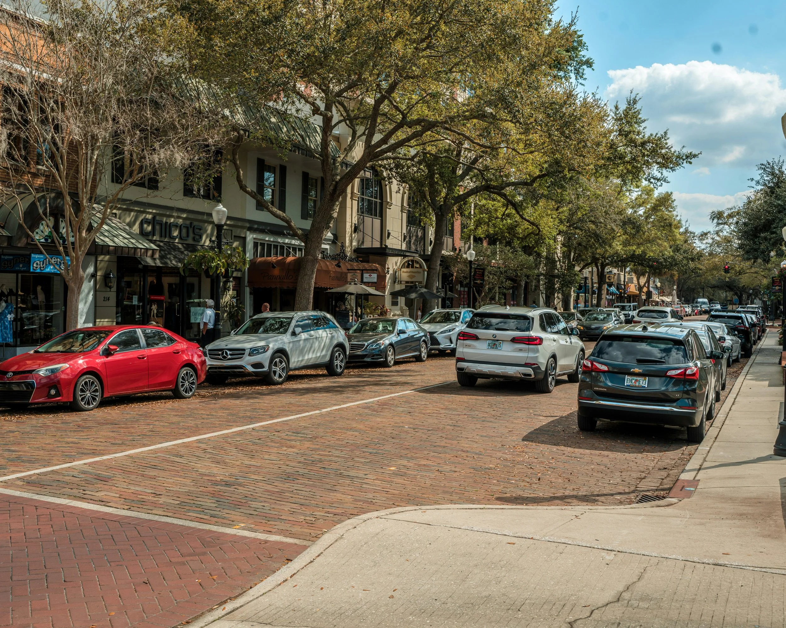 Shopfronts and parked cars along a busy street in downtown Winter Park