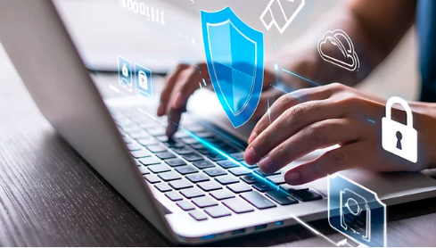 Main tapant sur un clavier d'ordinateur portable avec des icônes de sécurité numérique et de protection des données projetées à l'écran.