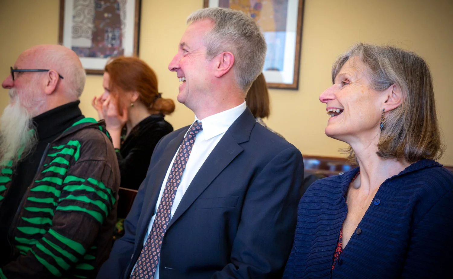 Group of people sitting in a room, smiling and laughing.