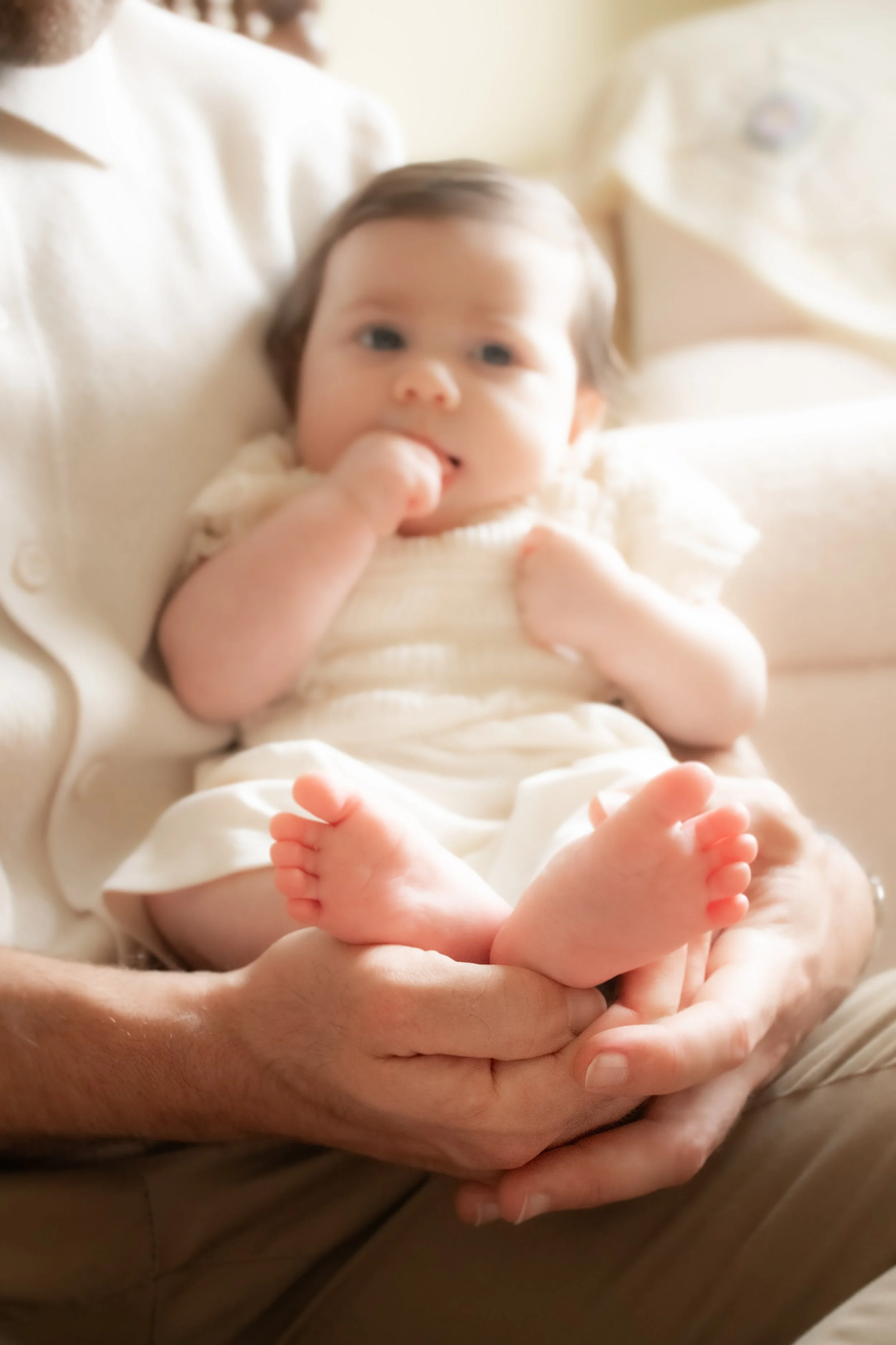 A close-up of a baby held by an adult, the baby's toes visible at the bottom of the frame.