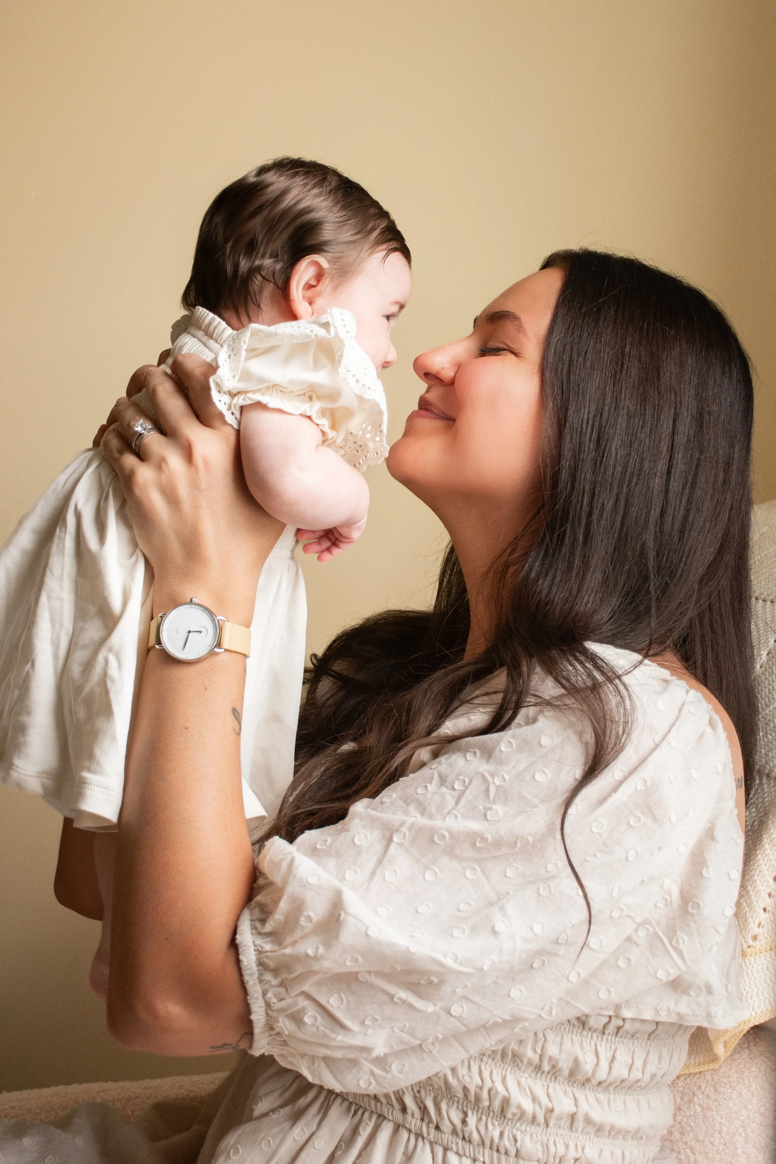 A mother holding her baby close to her face, both with their eyes closed.
