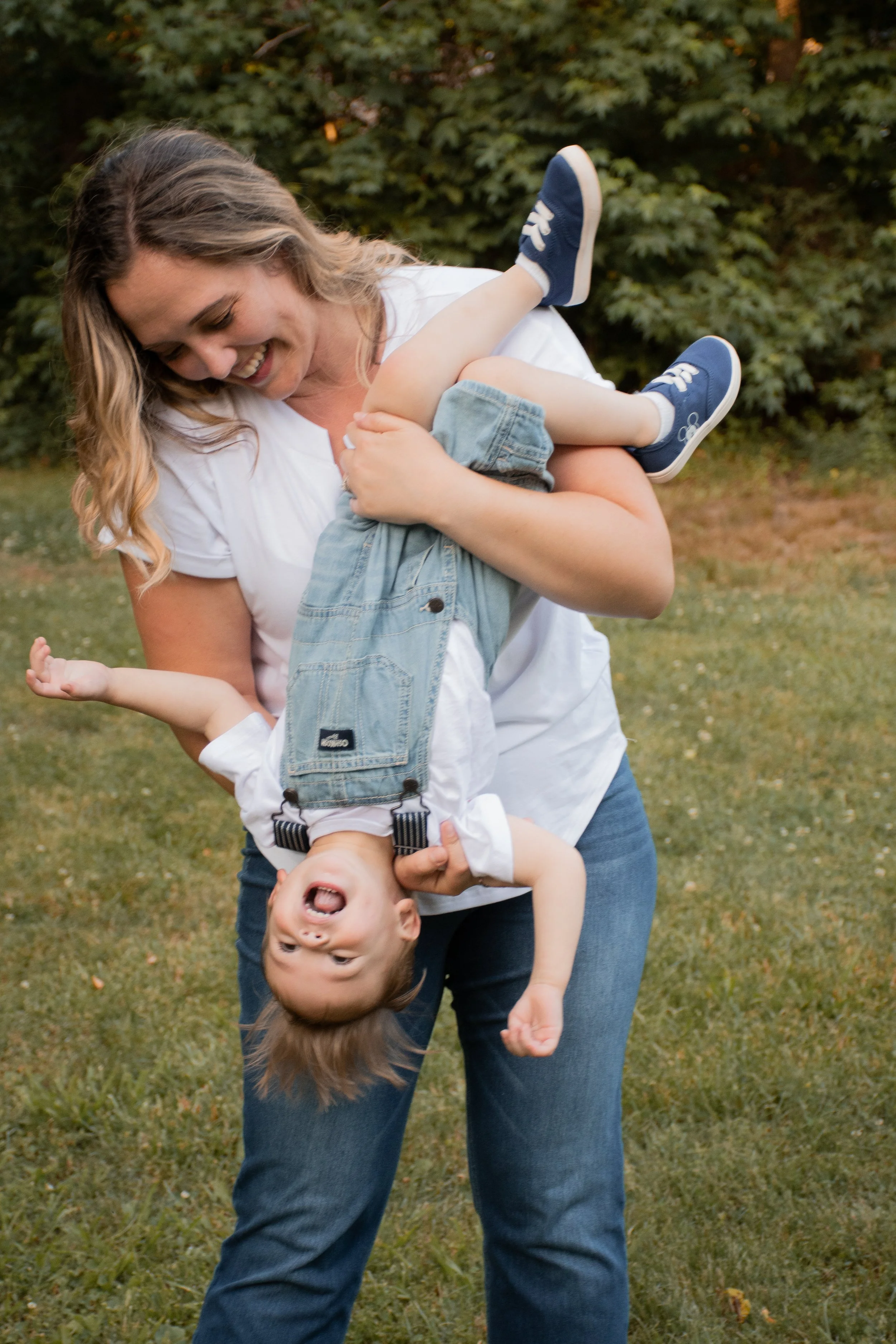 A woman holding a laughing toddler upside down