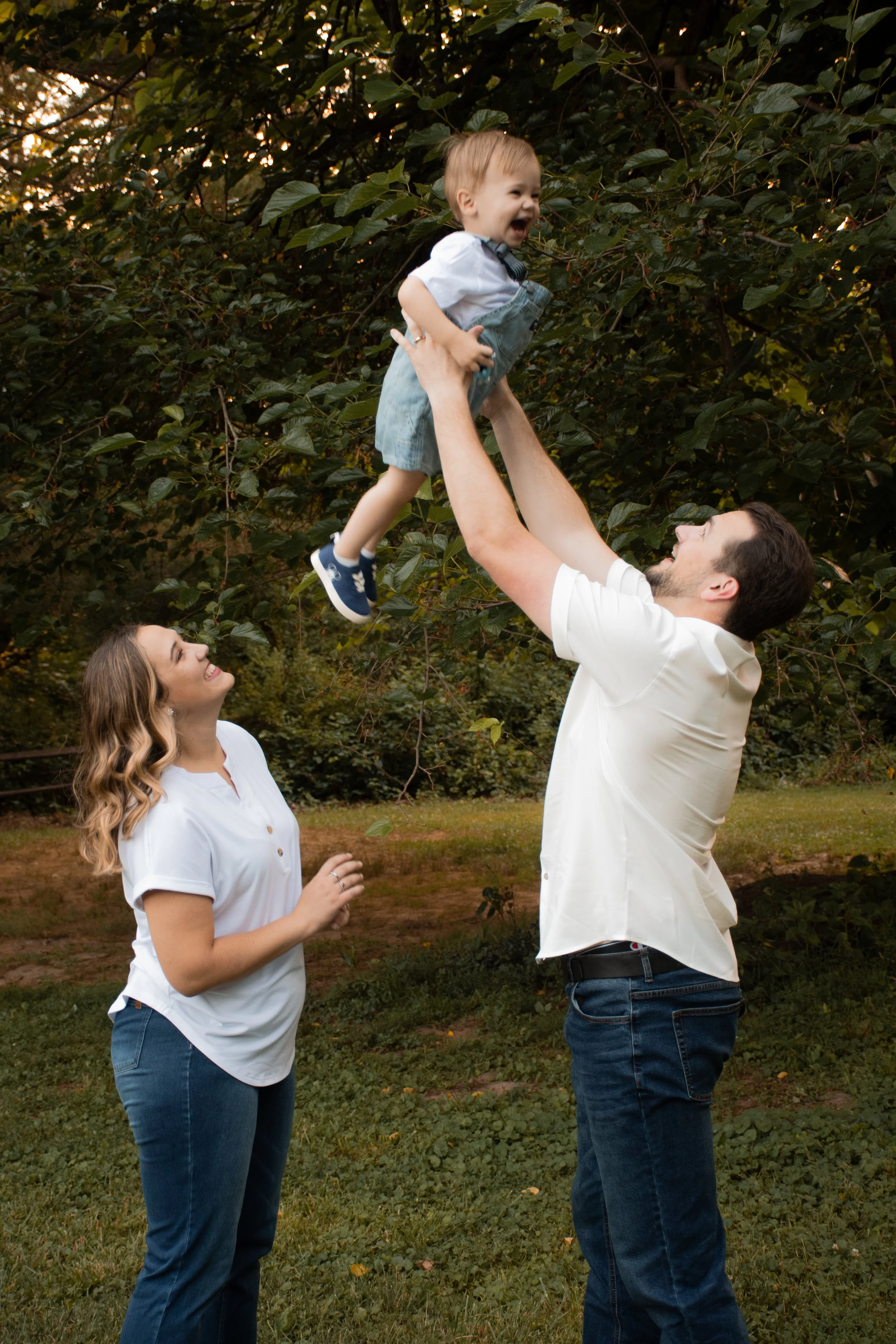 A man lifting a toddler overhead as a woman watches