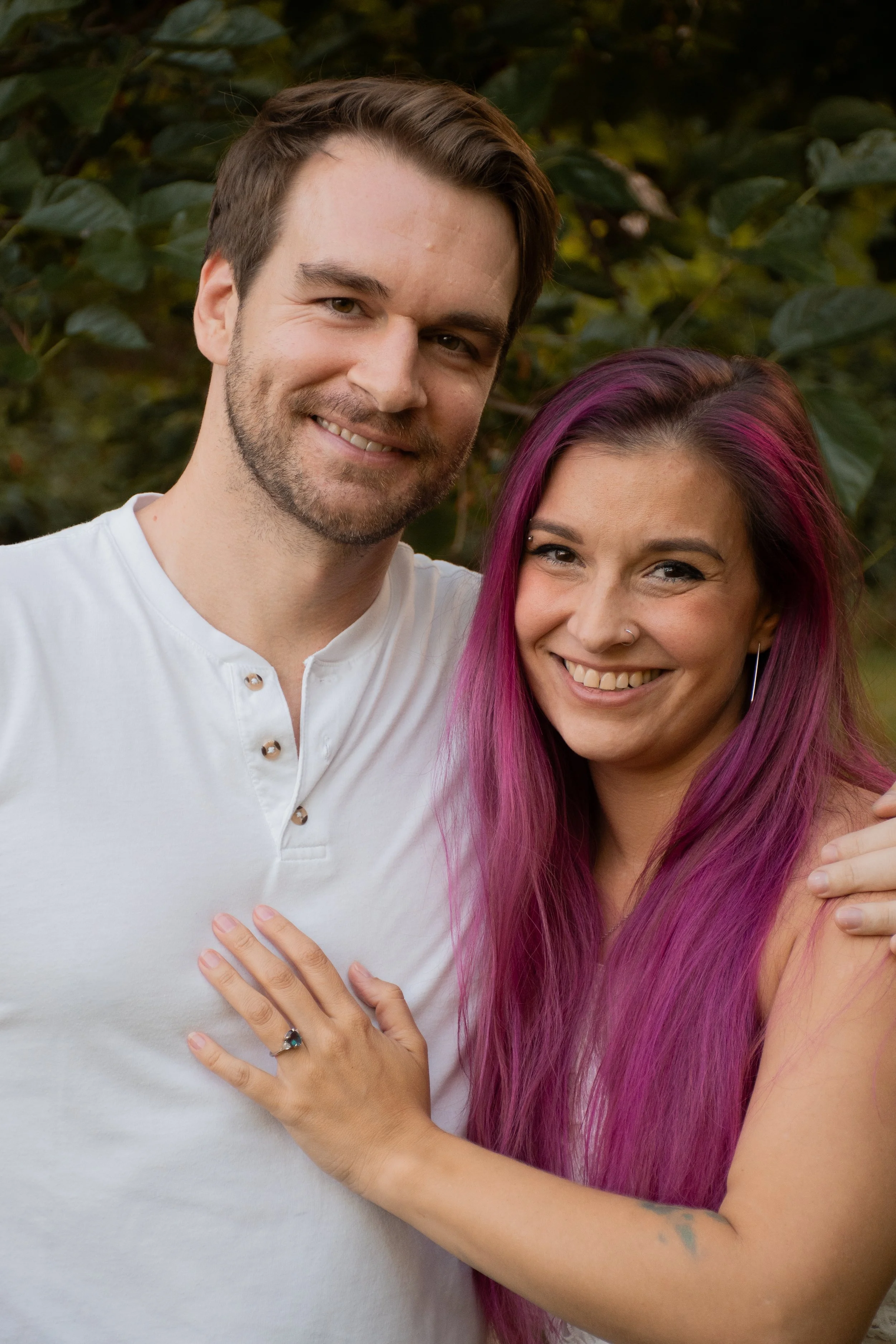  A couple smiling at the camera, her hand on his chest