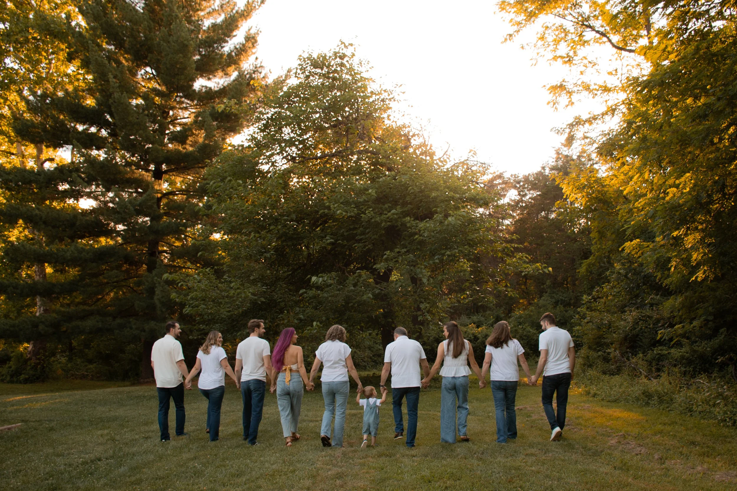  An extended family walking away together across a field at sunset