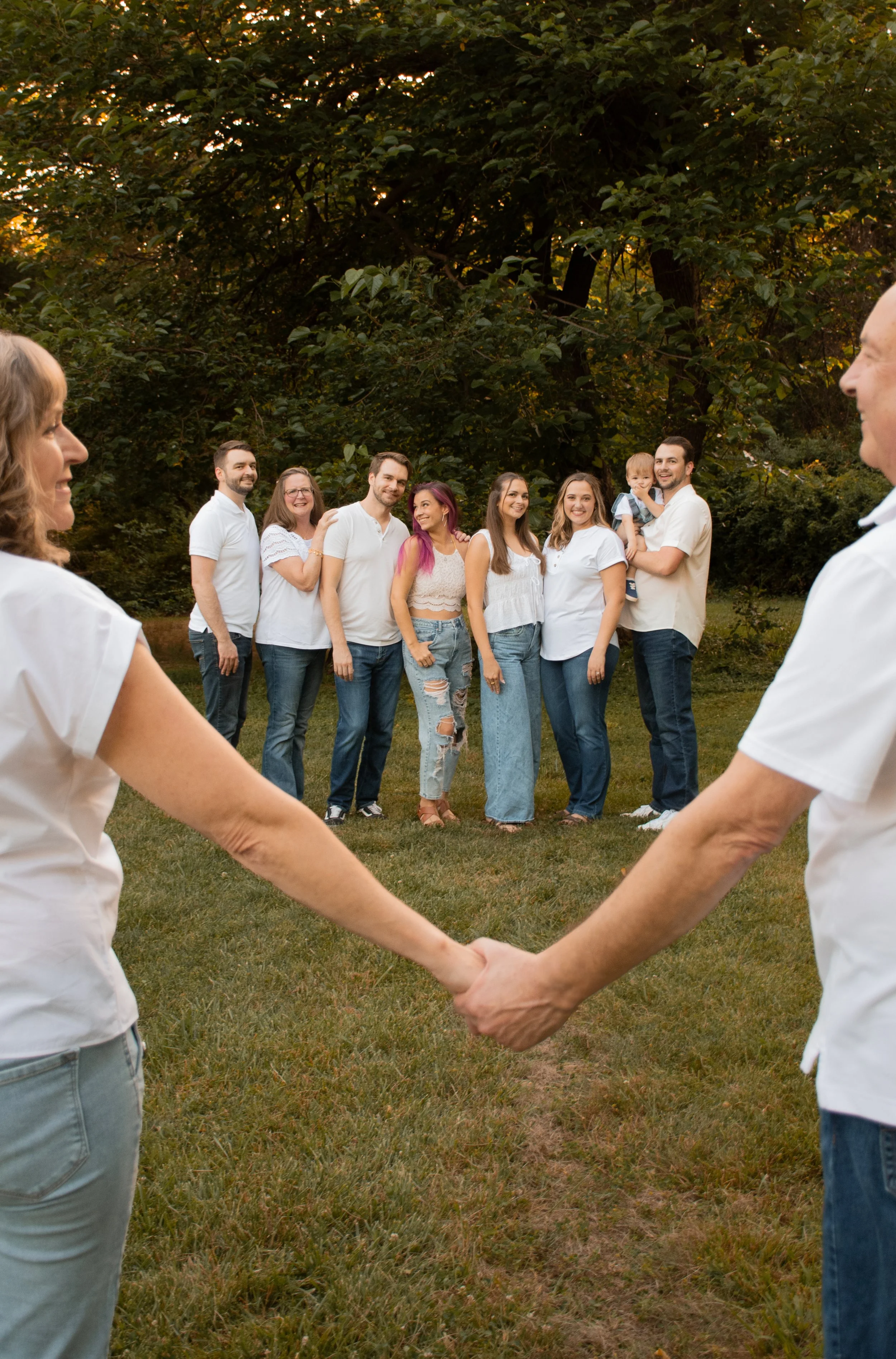 Two people holding hands in the foreground as their family stands together behind