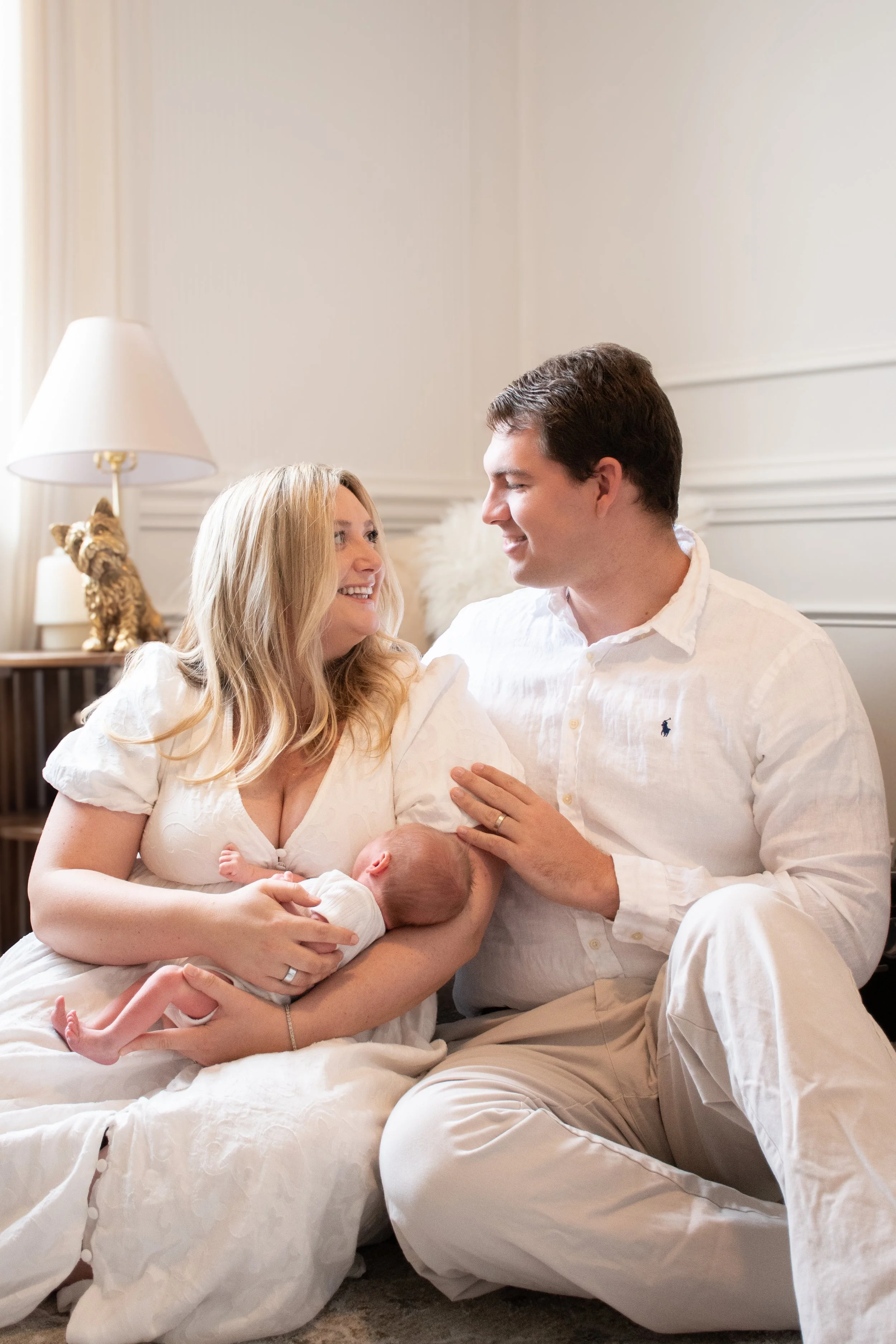  Parents sitting together on the floor, the mother cradling their newborn