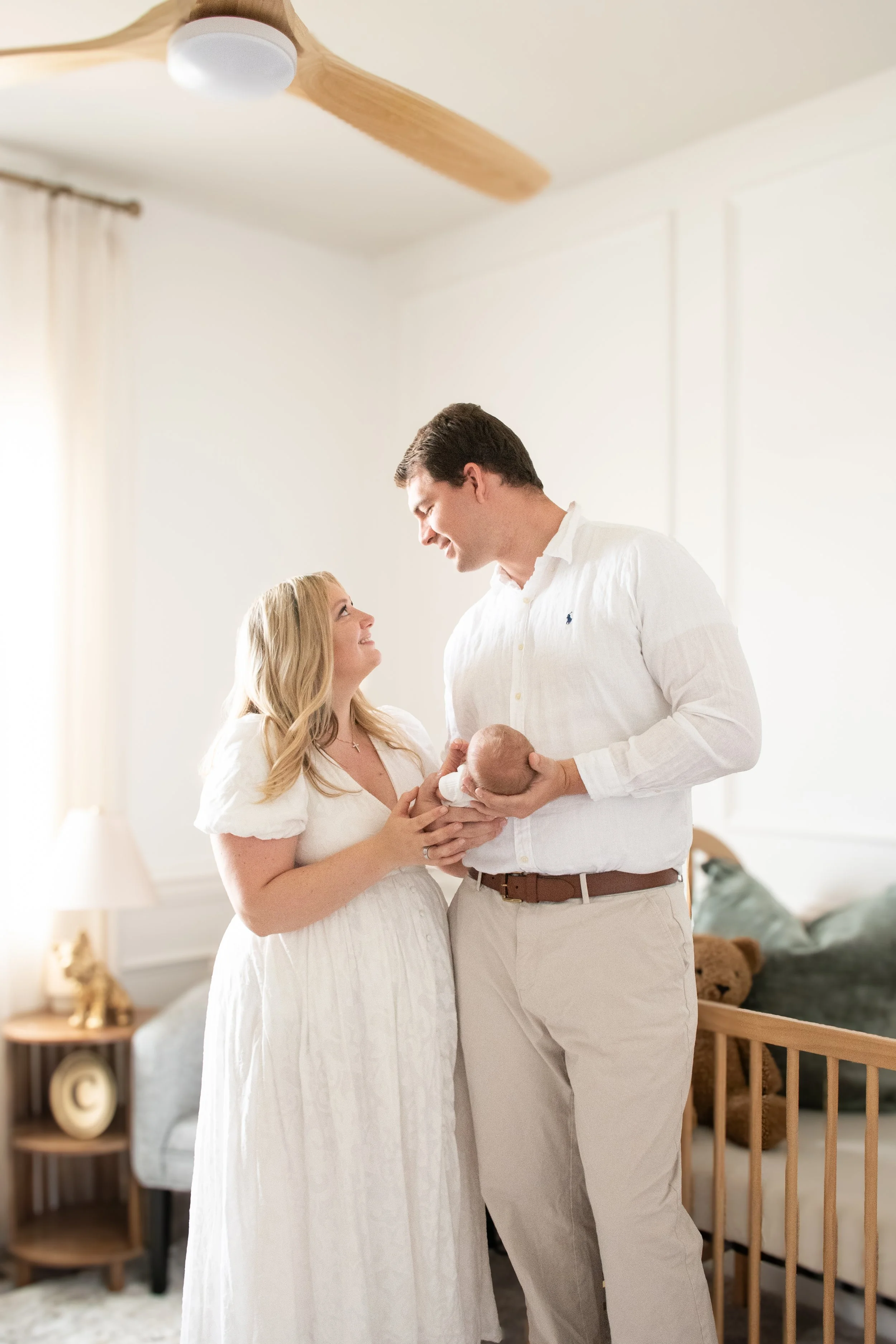 Parents standing together in the nursery holding their newborn
