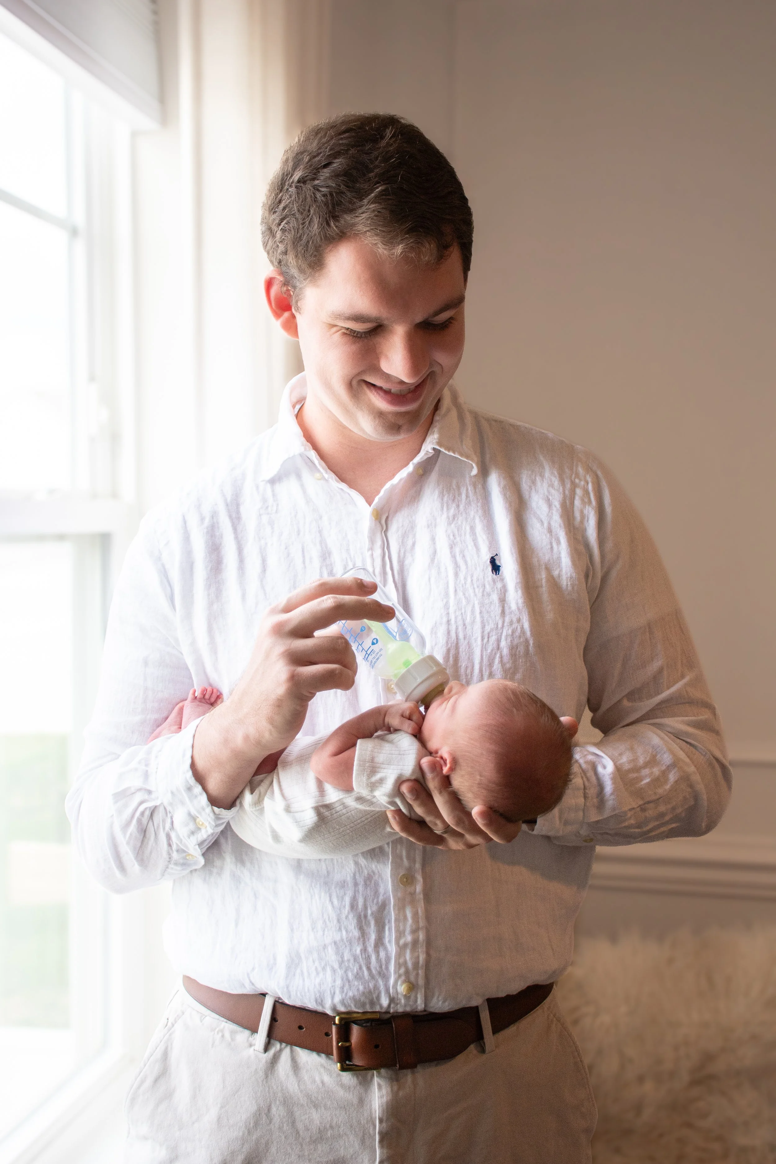A father holding his newborn by a window