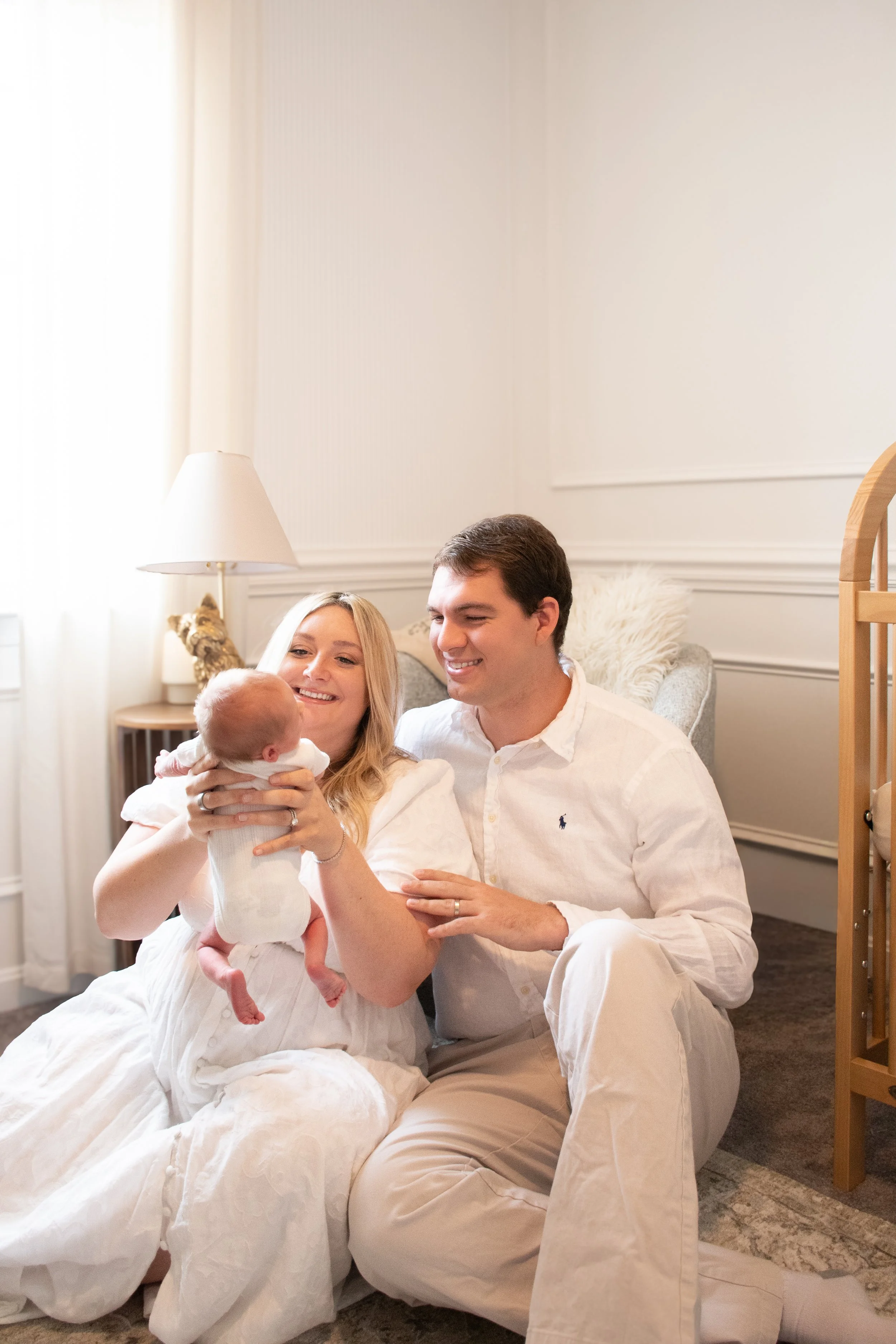  Parents sitting on the floor holding their newborn up between them