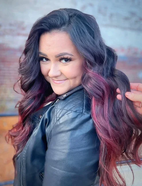 Person with long, wavy hair dyed in vibrant shades of green, yellow, and pink.