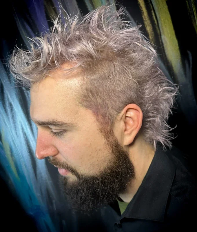 Back view of a person's shoulder-length wavy hair, colored with a rainbow gradient from purple at the roots, blending into pink, orange, and yellow towards the tips.