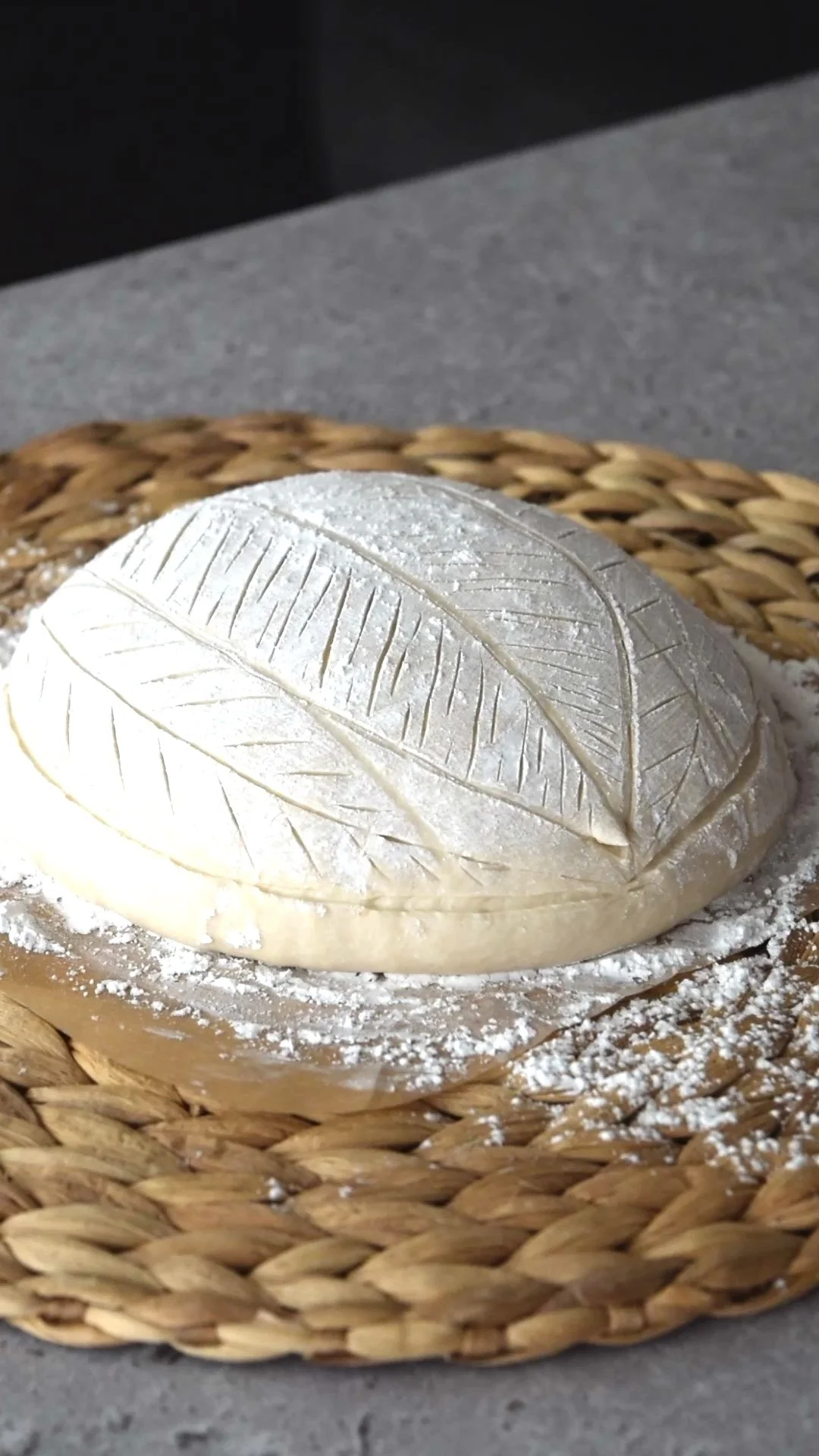 台の上にクープが施されたパン生地がのっている