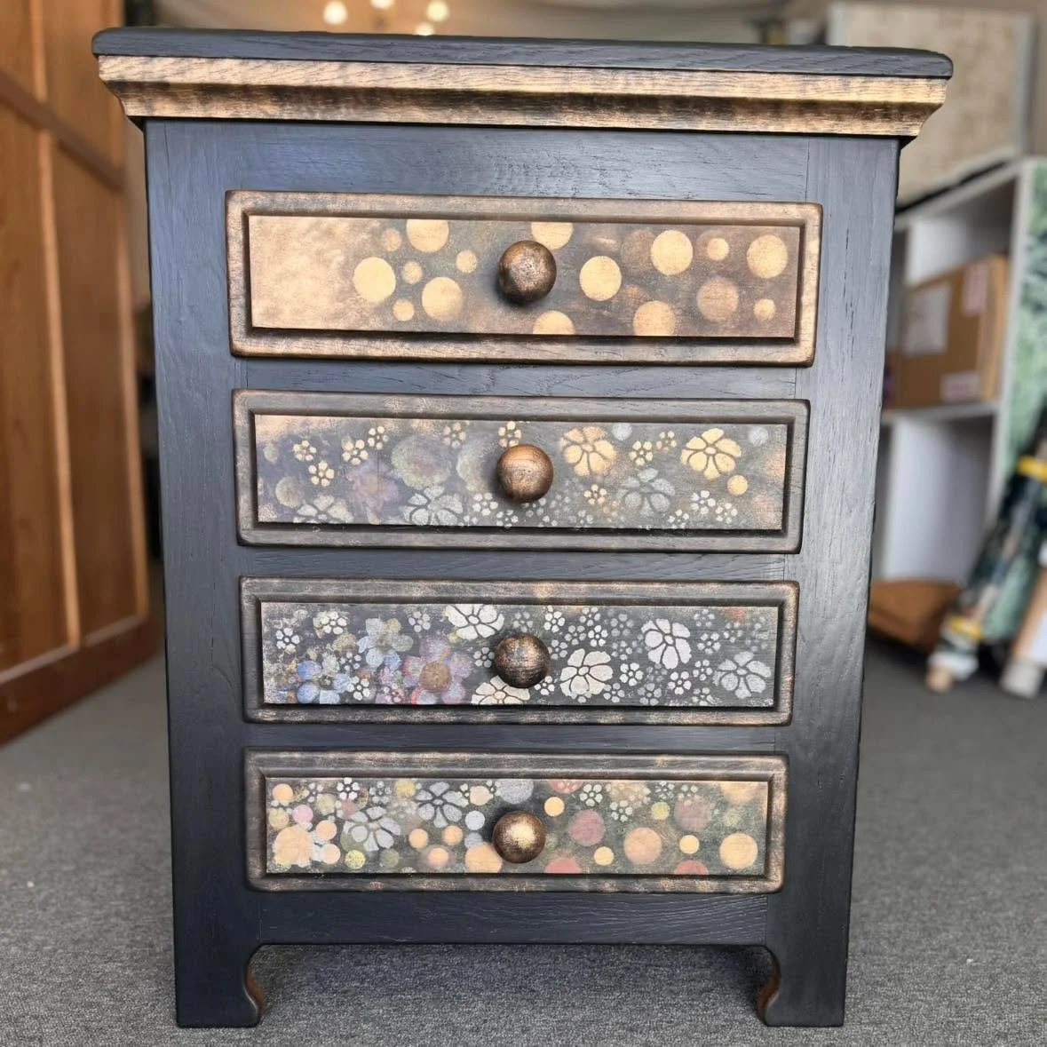 This cute little set of drawers was commissioned to complement a much larger piece we created for our lovely client in Norwich.
Using layered stencilling in Gold, Bronze, Rusty Orange, Pale Pink and Cream on a rich Black background we picked out the 