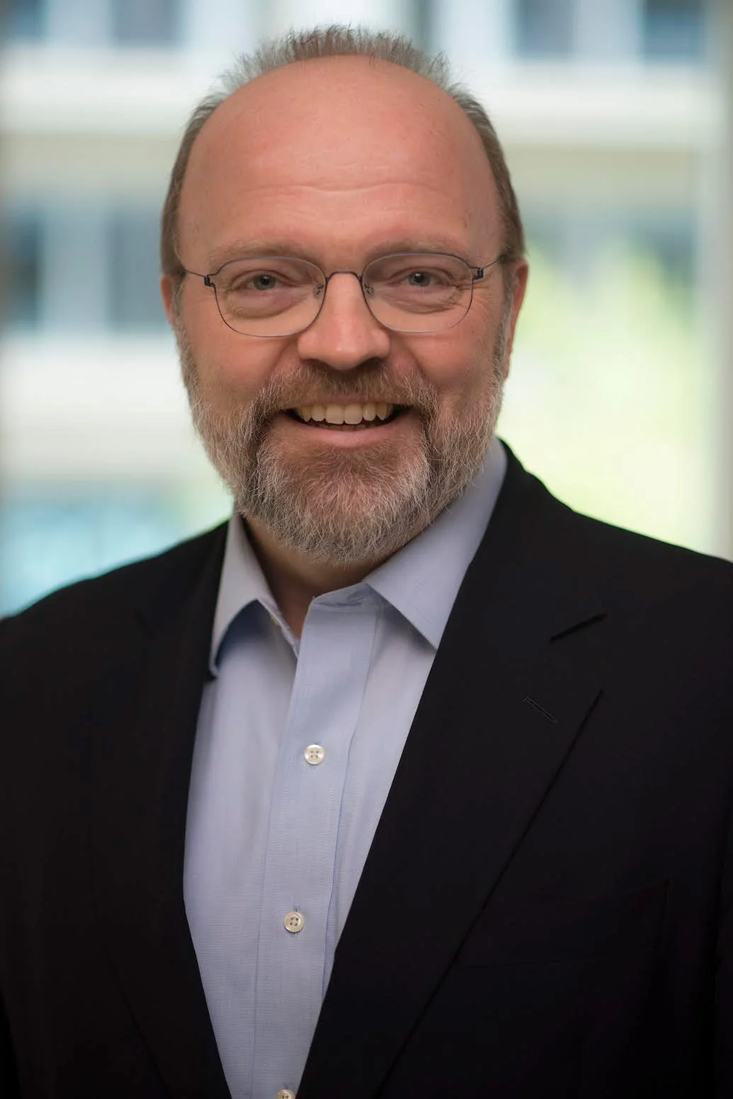 Bill Pierce, smiling in a blue button-down shirt and black blazer