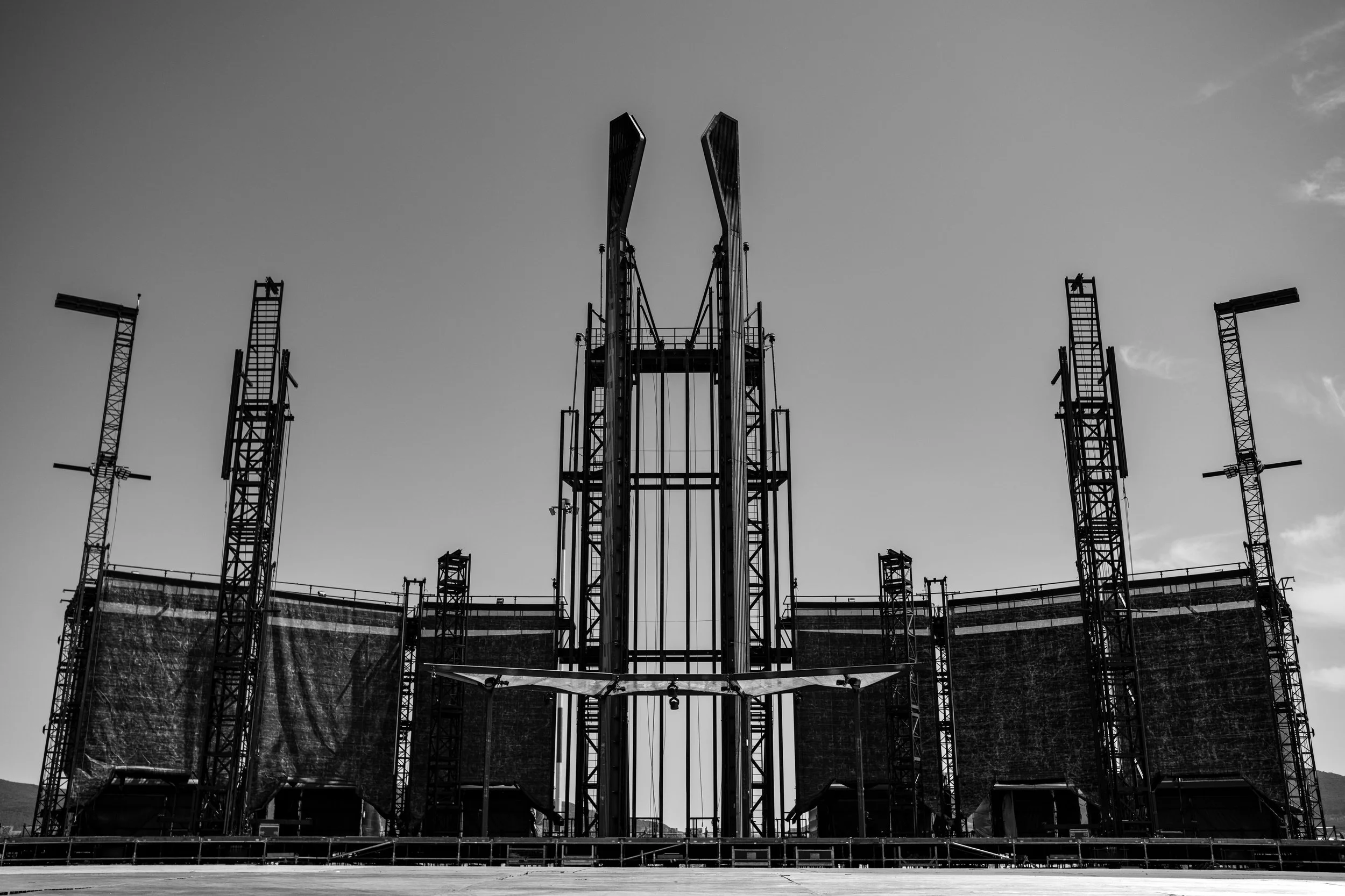 Black and white photo of a construction site with skyscraper frames and cranes against the sky.